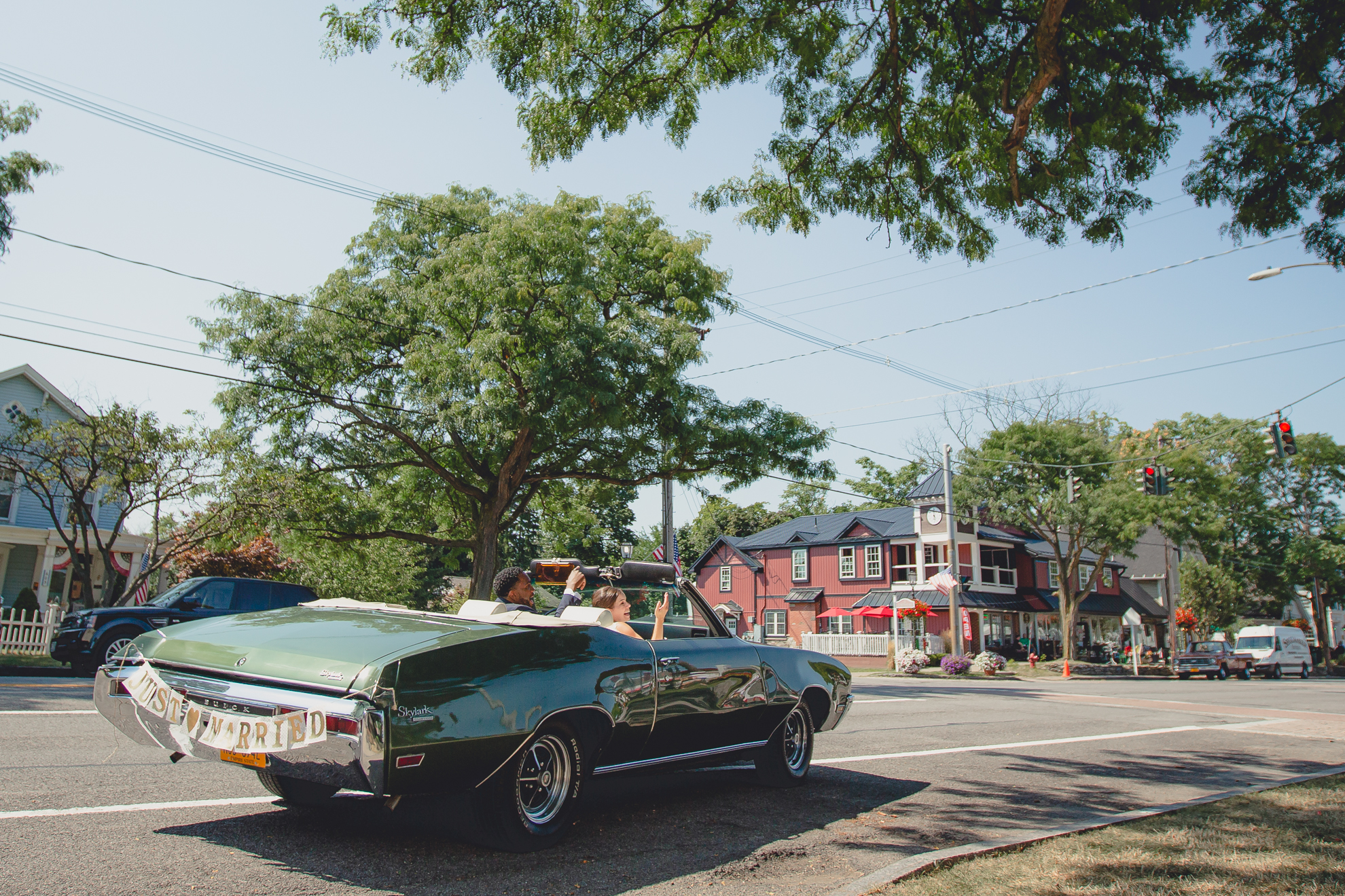 bride and groom drive away in vintage buick after micro wedding ceremony at St. Peter's Church in Lewiston, NY