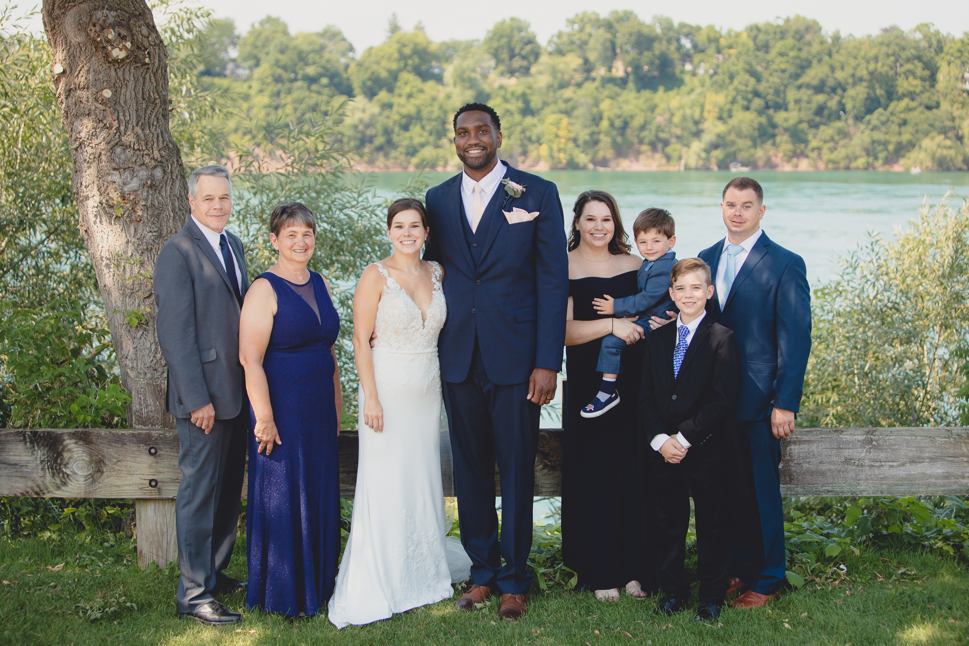 bride, groom families and wedding party smile for photographer during wedding portraits at Lewiston Landing during WNY micro wedding