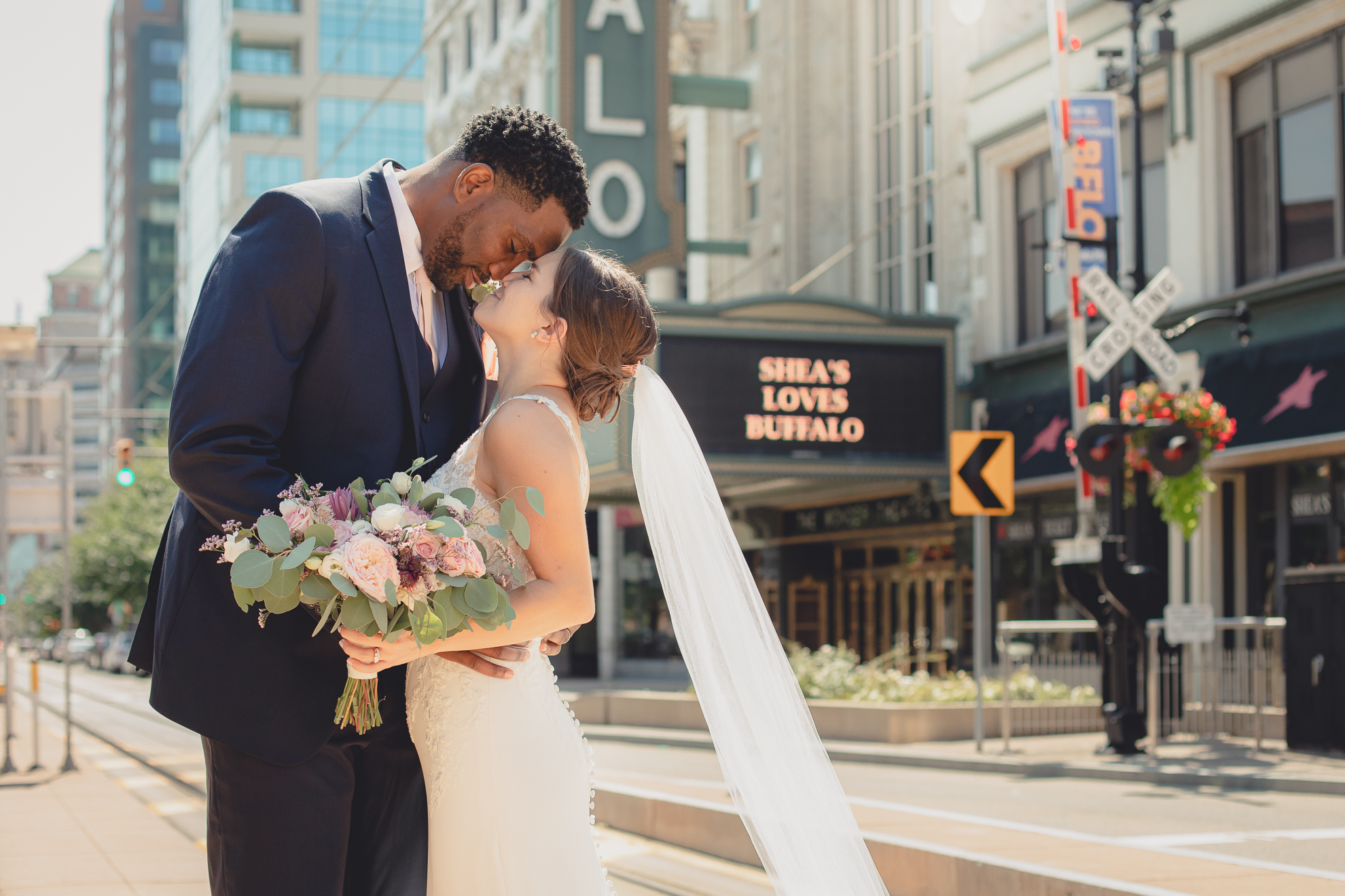 bride and groom touching noses in theater district of Buffalo, NY near Shea's Theater during WNY micro wedding celebration