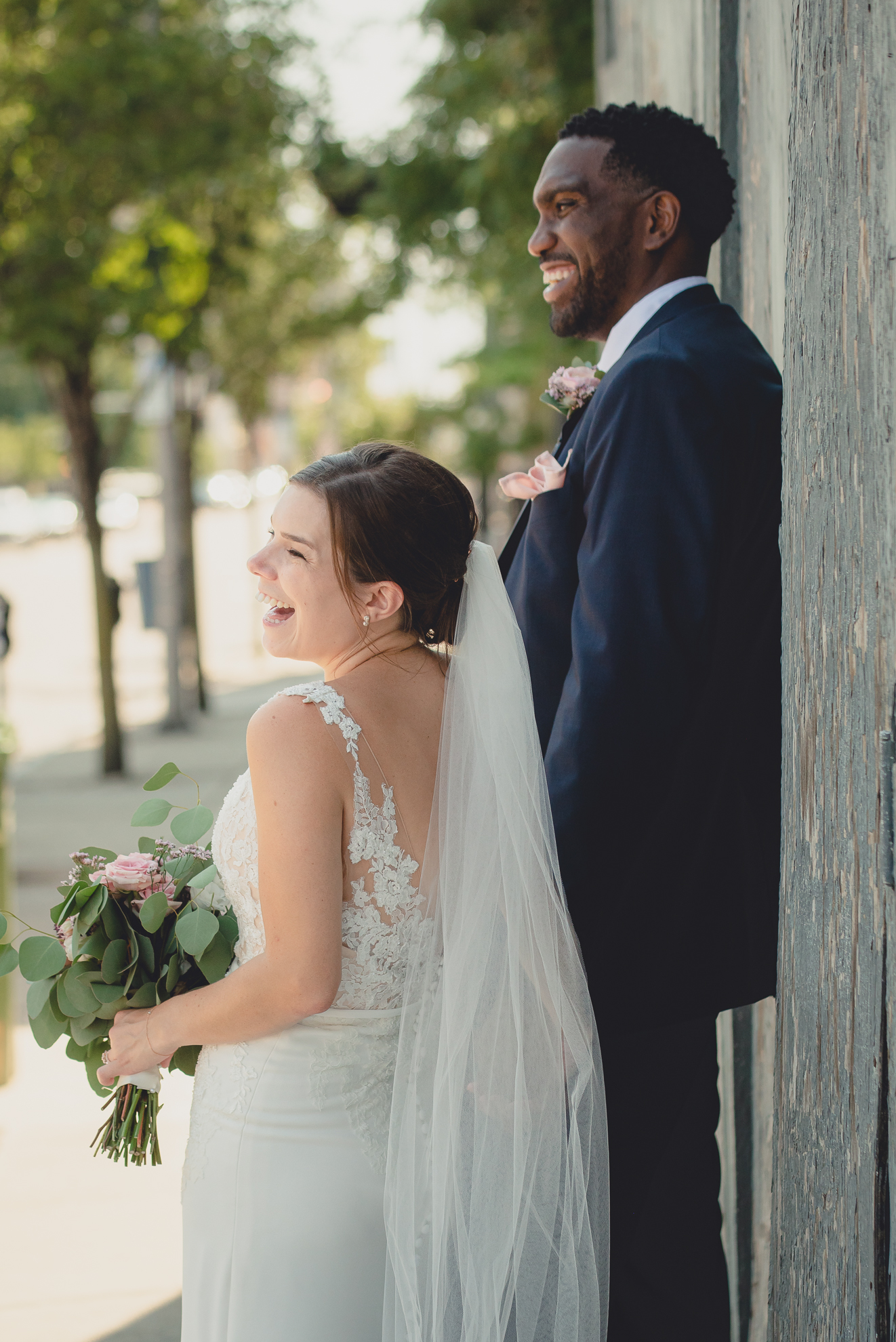 bride and groom laugh in theater district of Buffalo, NY near Shea's Theater during WNY micro wedding celebration