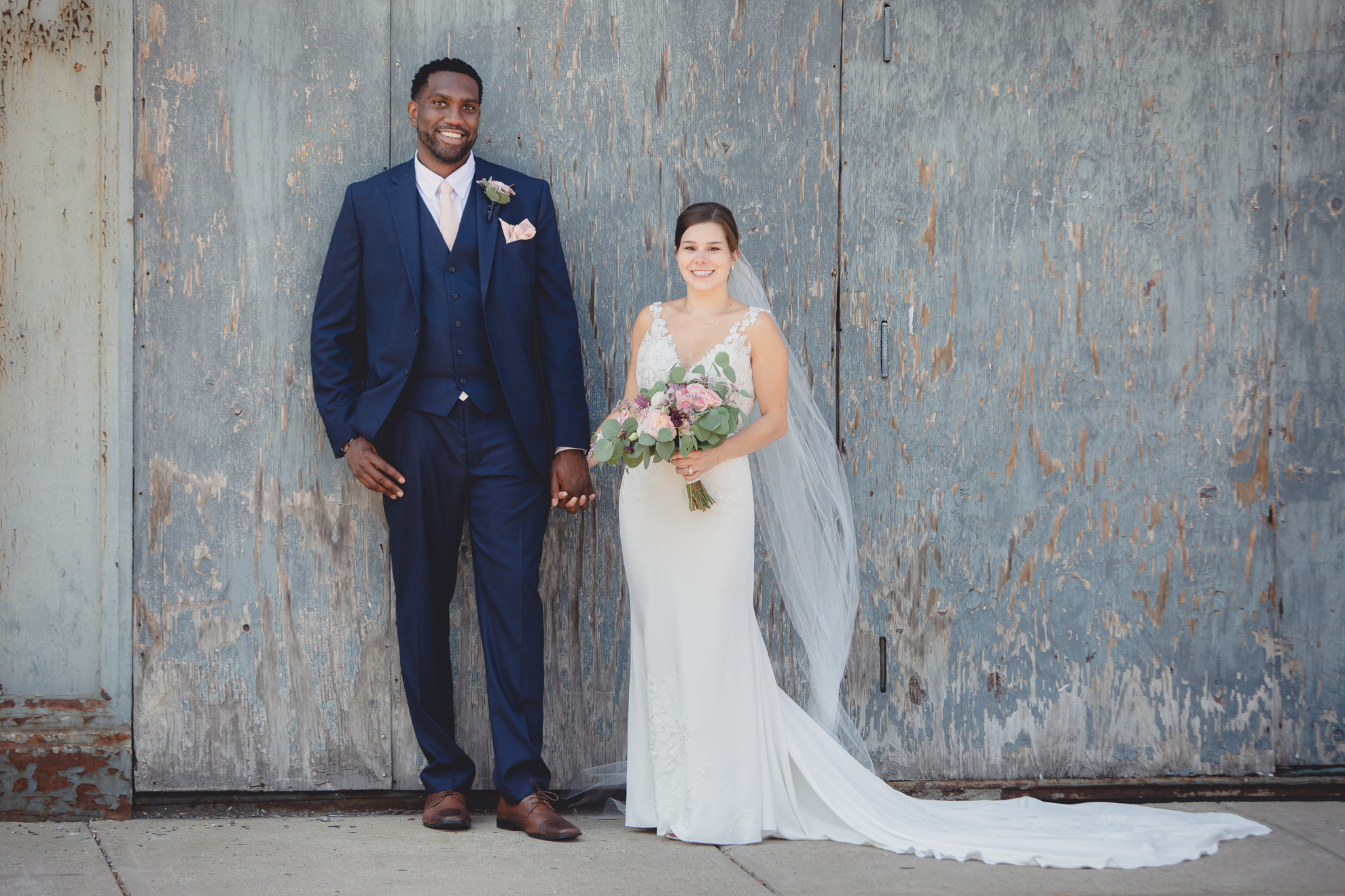 bride and groom smile for photographer in theater district of Buffalo, NY near Shea's Theater during WNY micro wedding celebration