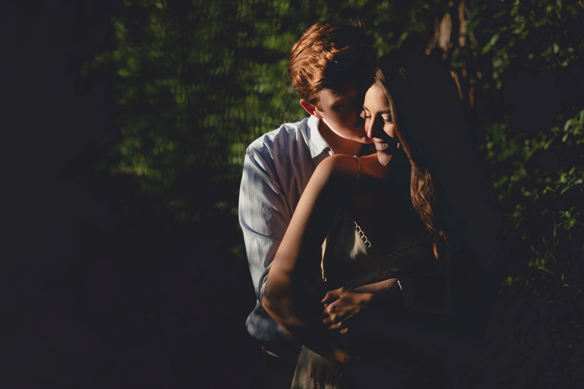 groom kisses bride on cheek during wedding engagement portrait photography session at tifft nature preserve in Buffalo, NY