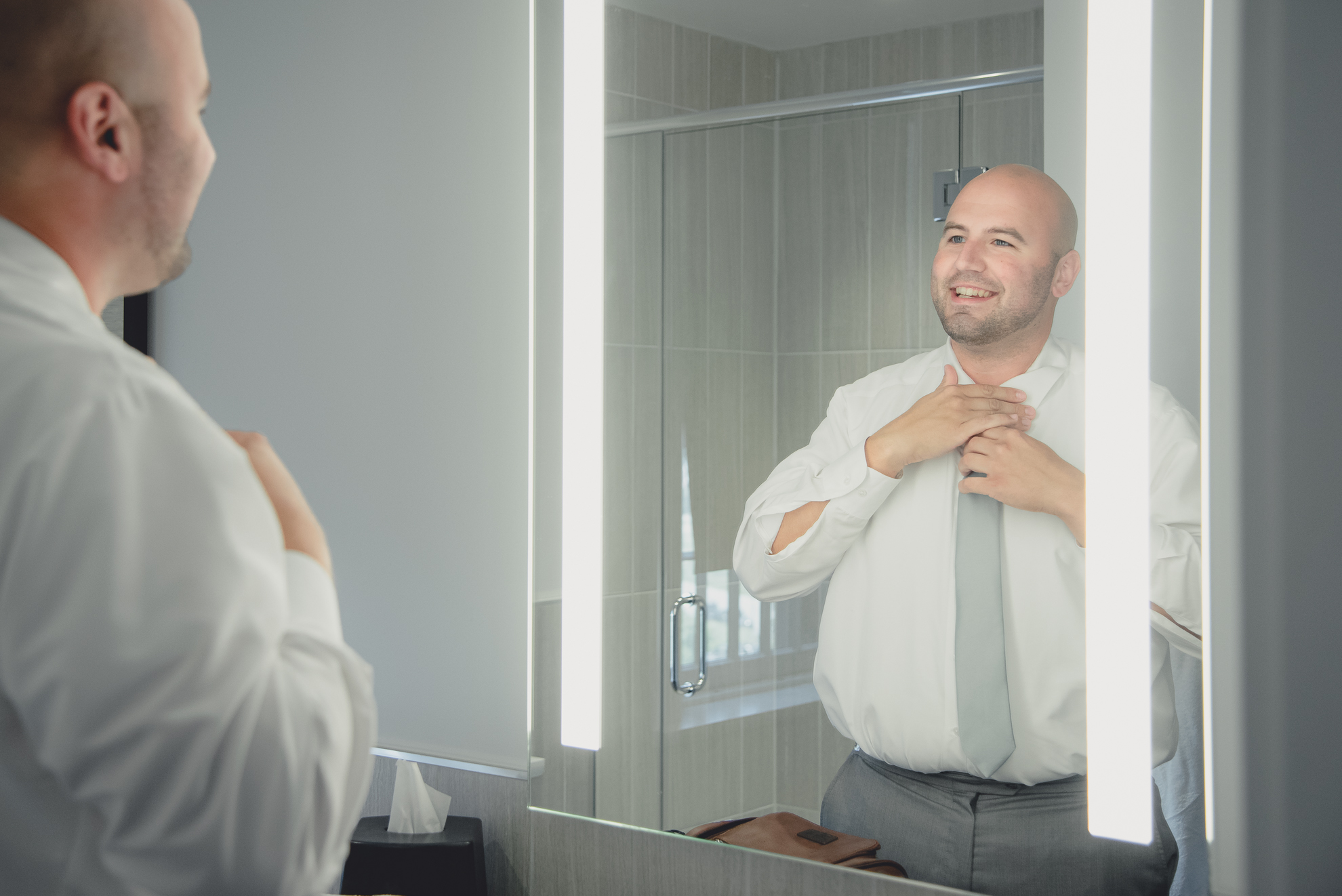 groom adjusts tie before wedding at Hotel Henry in Buffalo, NY