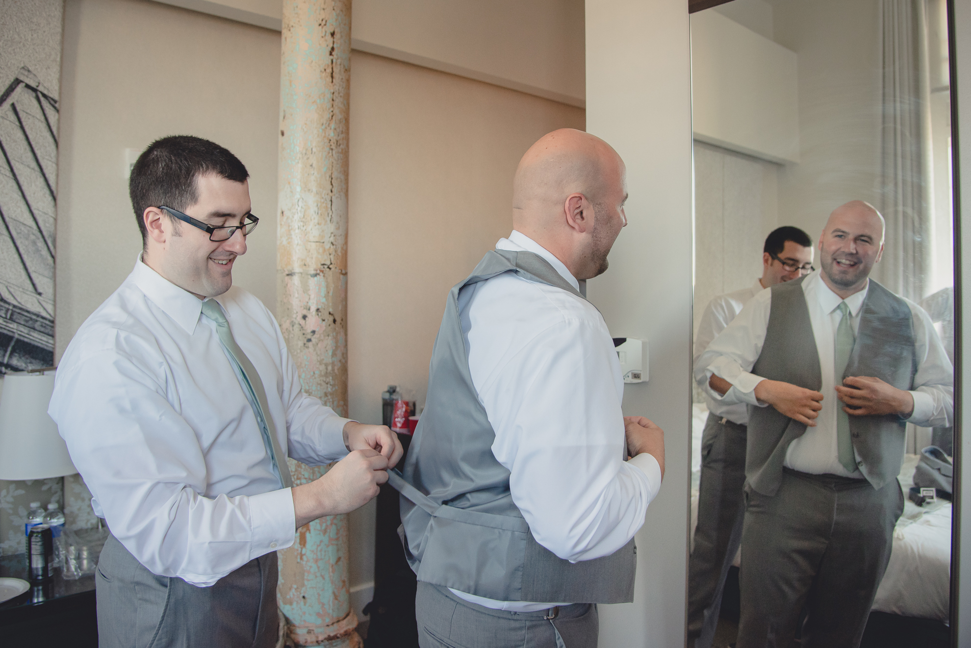 bestman adjusts grooms vest before wedding at Hotel Henry in Buffalo, NY