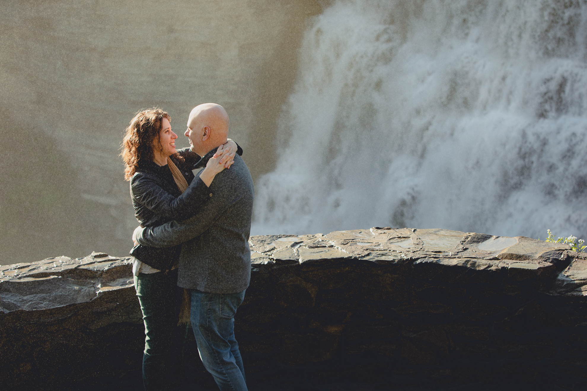 bride and groom look at eachother smiling after wedding proposal next to Middle Falls at Letchworth State Park near Buffalo, NY