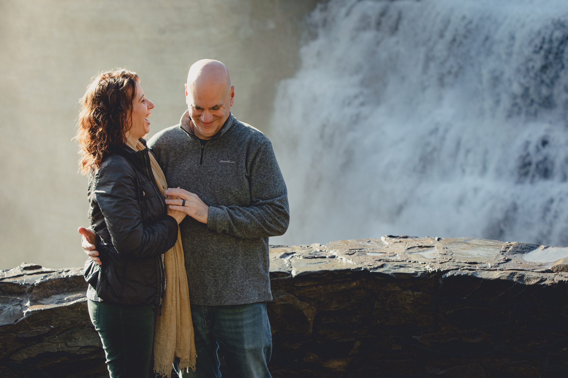 bride and groom laugh after wedding proposal next to Middle Falls at Letchworth State Park near Buffalo, NY
