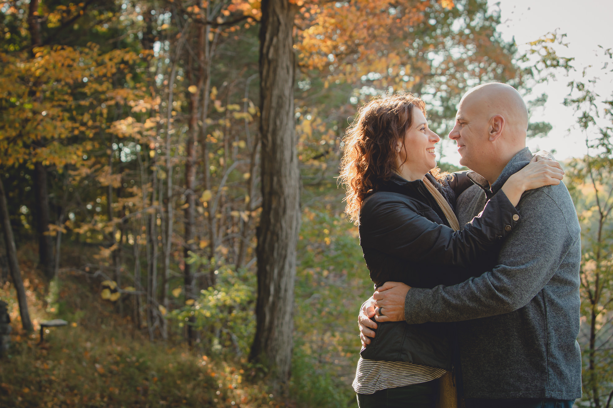 bride and groom pose in front of fall foliage in forest after wedding proposal next to Middle Falls at Letchworth State Park near Buffalo, NY