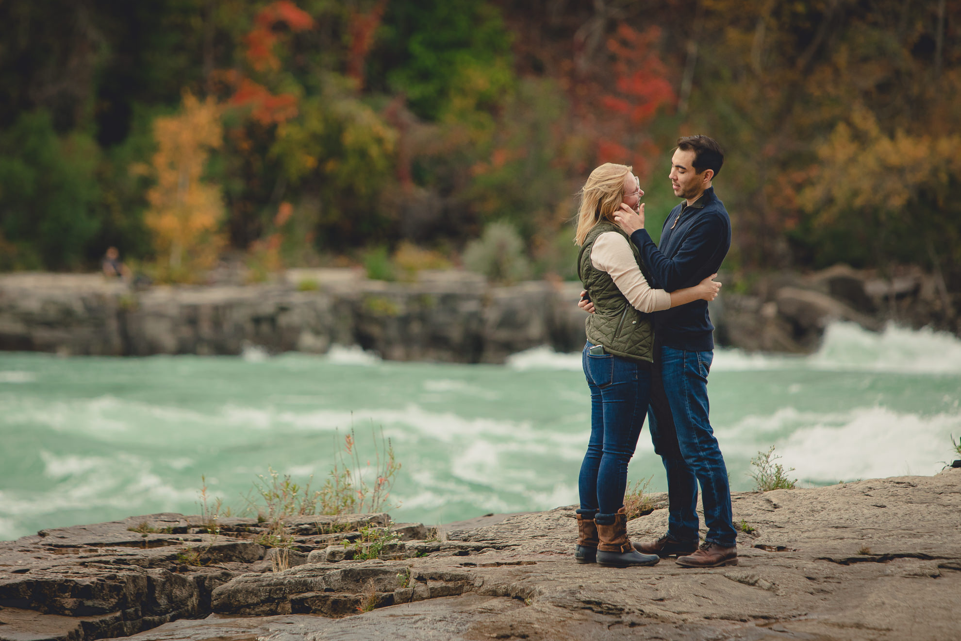 couple cries after wedding engagement proposal photography with rapids and fall foliage in background at Whirlpool State Park in Niagara Falls, NY