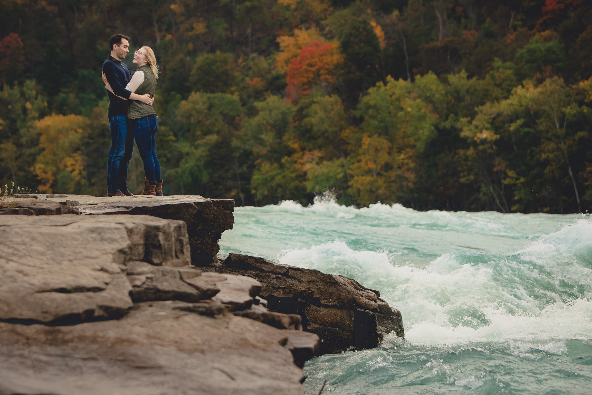 bride and groom admire rapids and fall foliage before wedding engagement proposal in Whirlpool State Park in Niagara Falls, NY