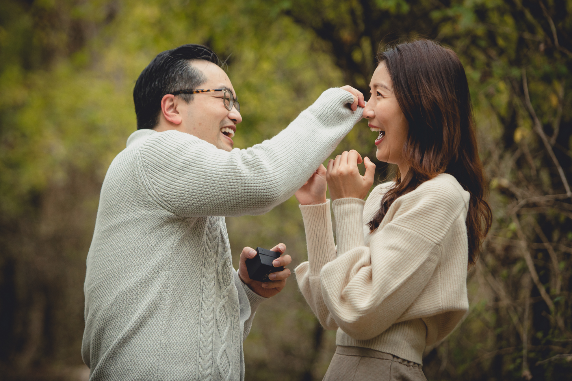 man wipes woman's tears with sweater sleeve during wedding engagement proposal at Tifft Nature Preserve in Buffalo, NY