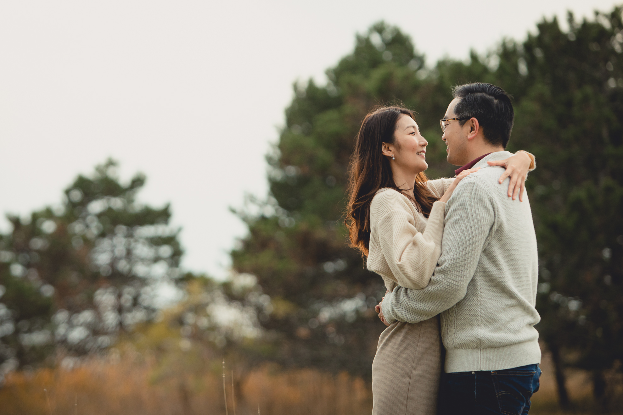 bride and groom embrace in front of pine trees after wedding engagement proposal at Tifft Nature Preserve in Buffalo, NY