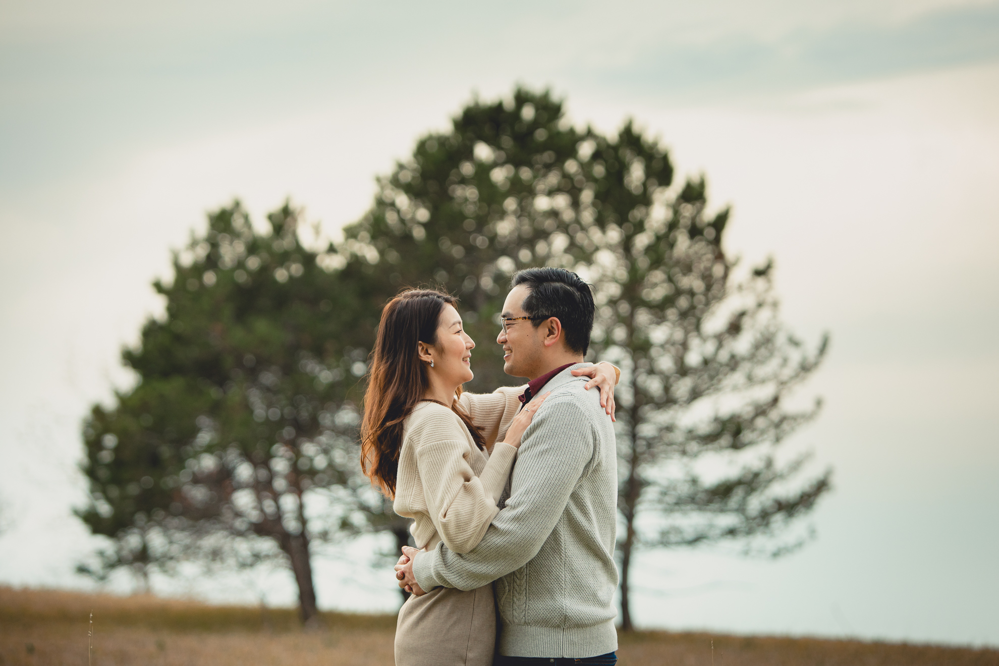 bride and groom embrace in front of pine trees after wedding engagement proposal at Tifft Nature Preserve in Buffalo, NY