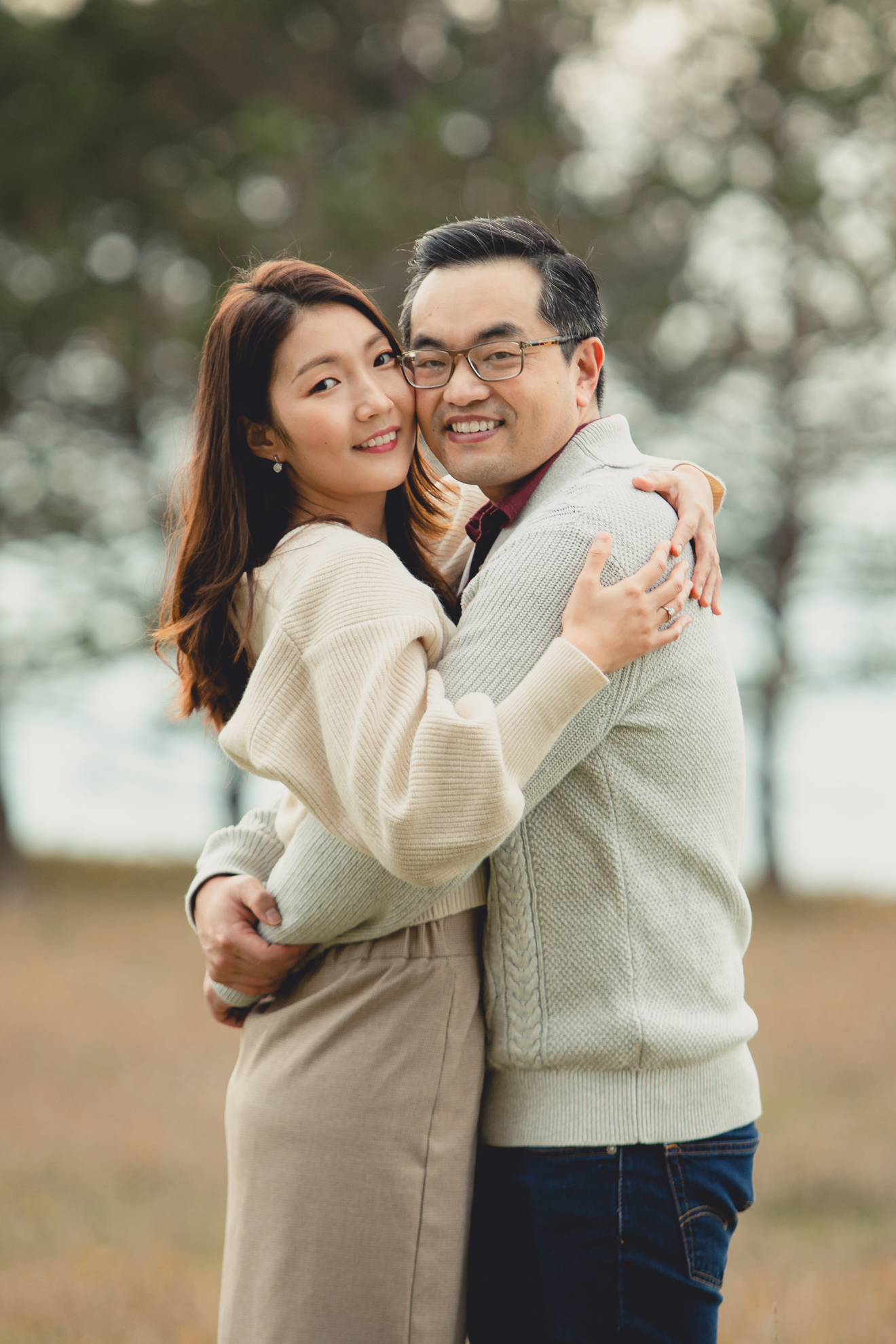 bride and groom smile for photographer in front of pine trees after wedding engagement proposal at Tifft Nature Preserve in Buffalo, NY