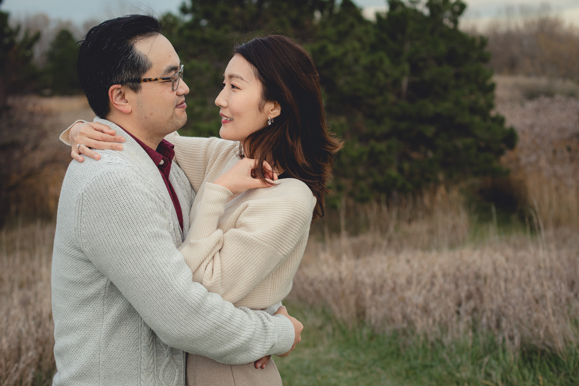 bride and groom embrace in front of pine trees after wedding engagement proposal at Tifft Nature Preserve in Buffalo, NY