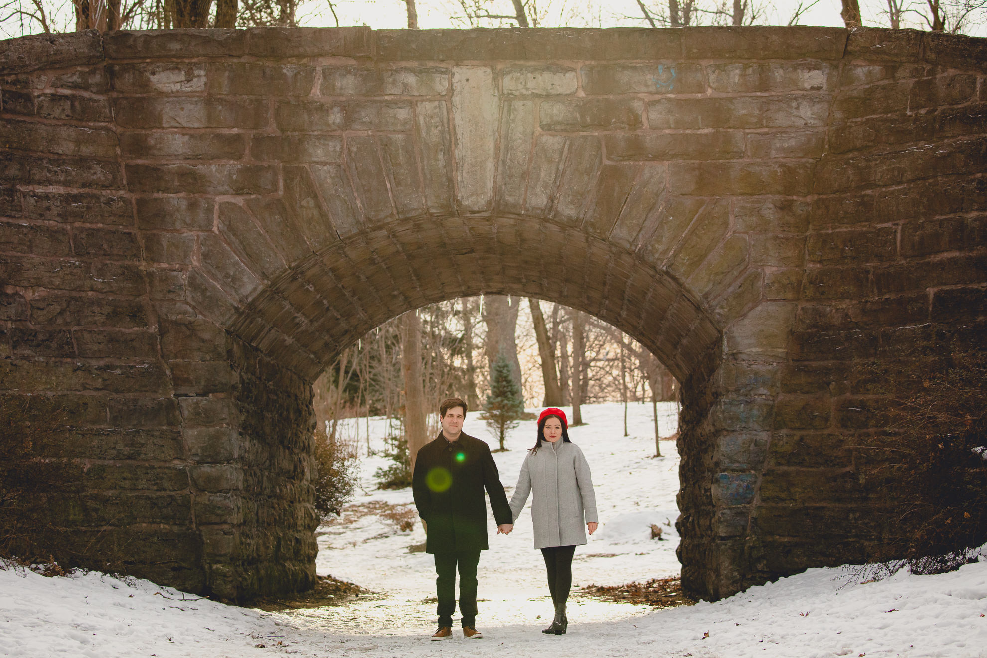 bride and groom smile at photographer in front of the Ivy Bridge in Delaware Park during their wedding engagement photography session in Buffalo, NY