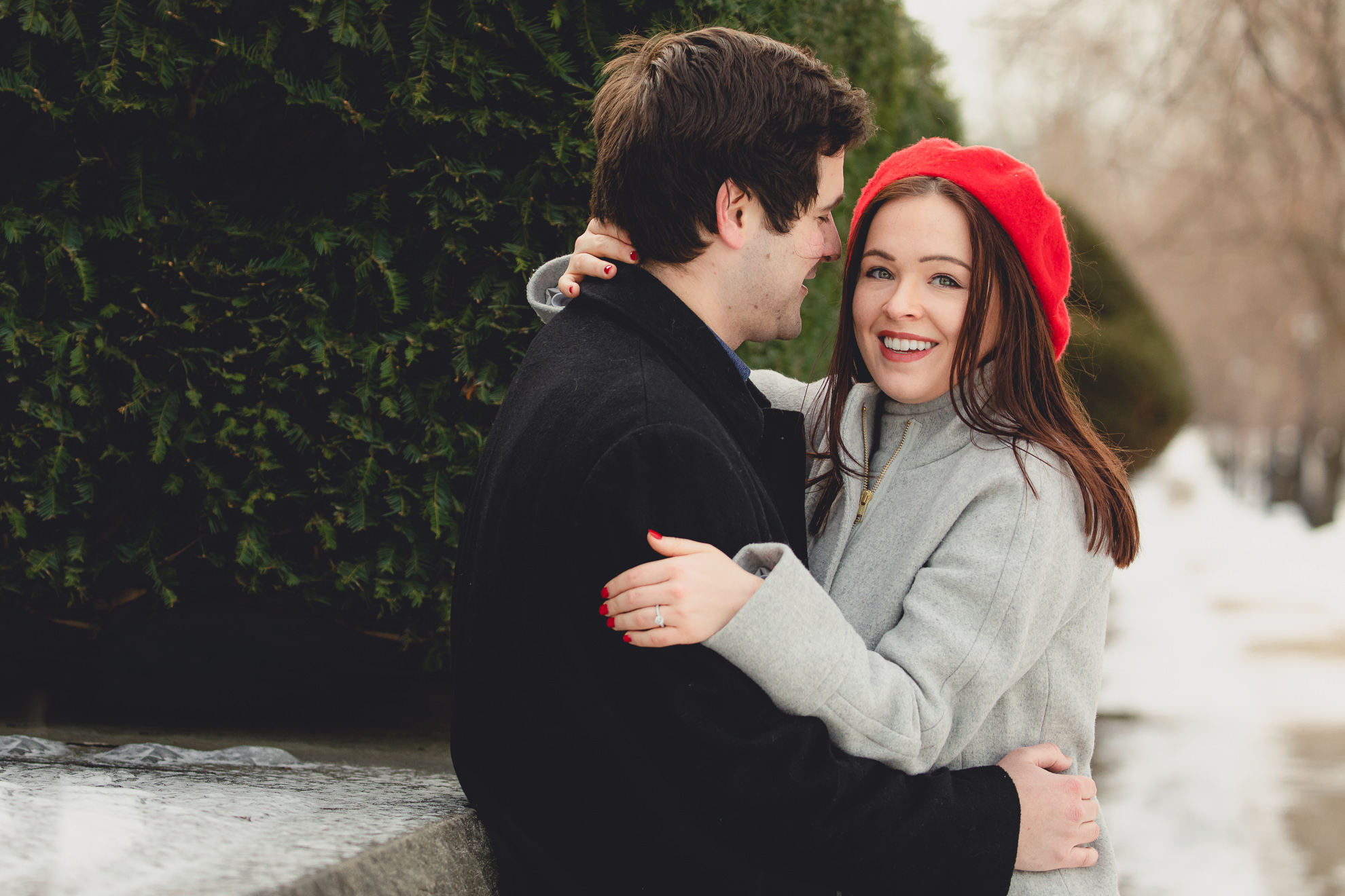 groom whispers secret to bride on Lincoln Parkway in Delaware Park during their wedding engagement photography session in Buffalo, NY