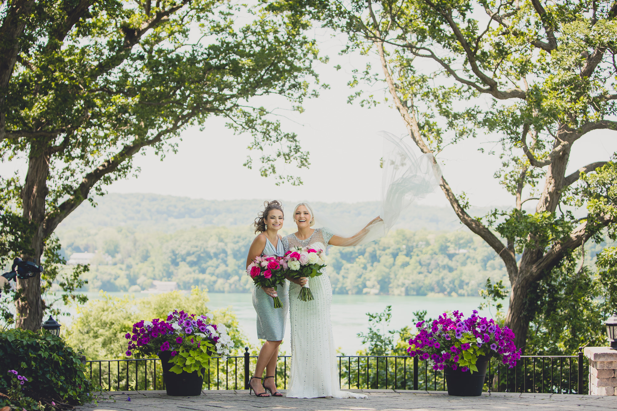 bride poses for portrait with sister in backyard along the Niagara River in Lewiston, NY