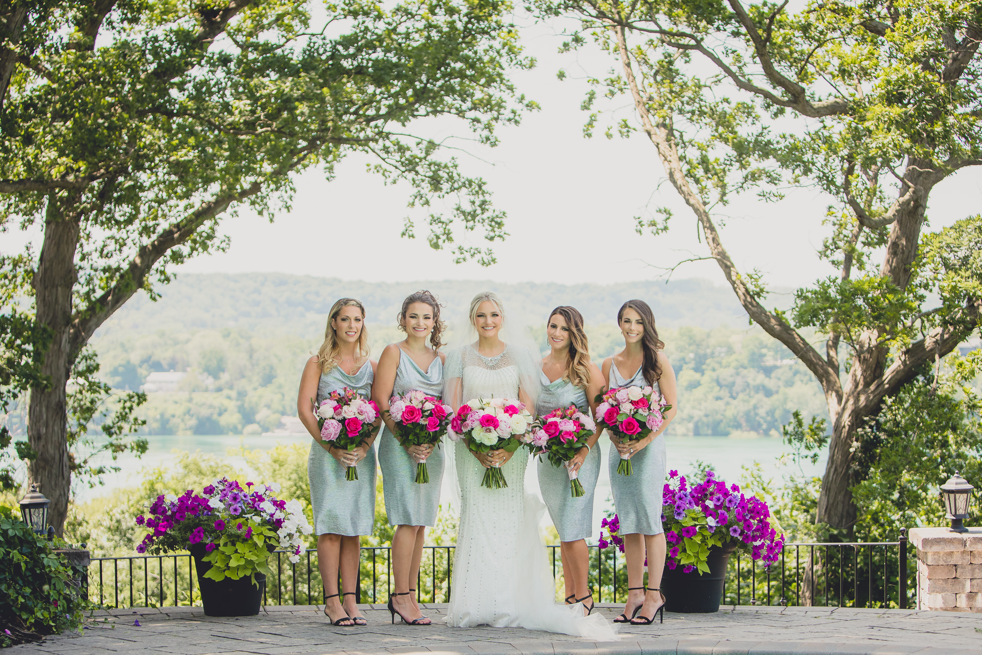 bride poses for portrait with bridesmaids in backyard along the Niagara River in Lewiston, NY