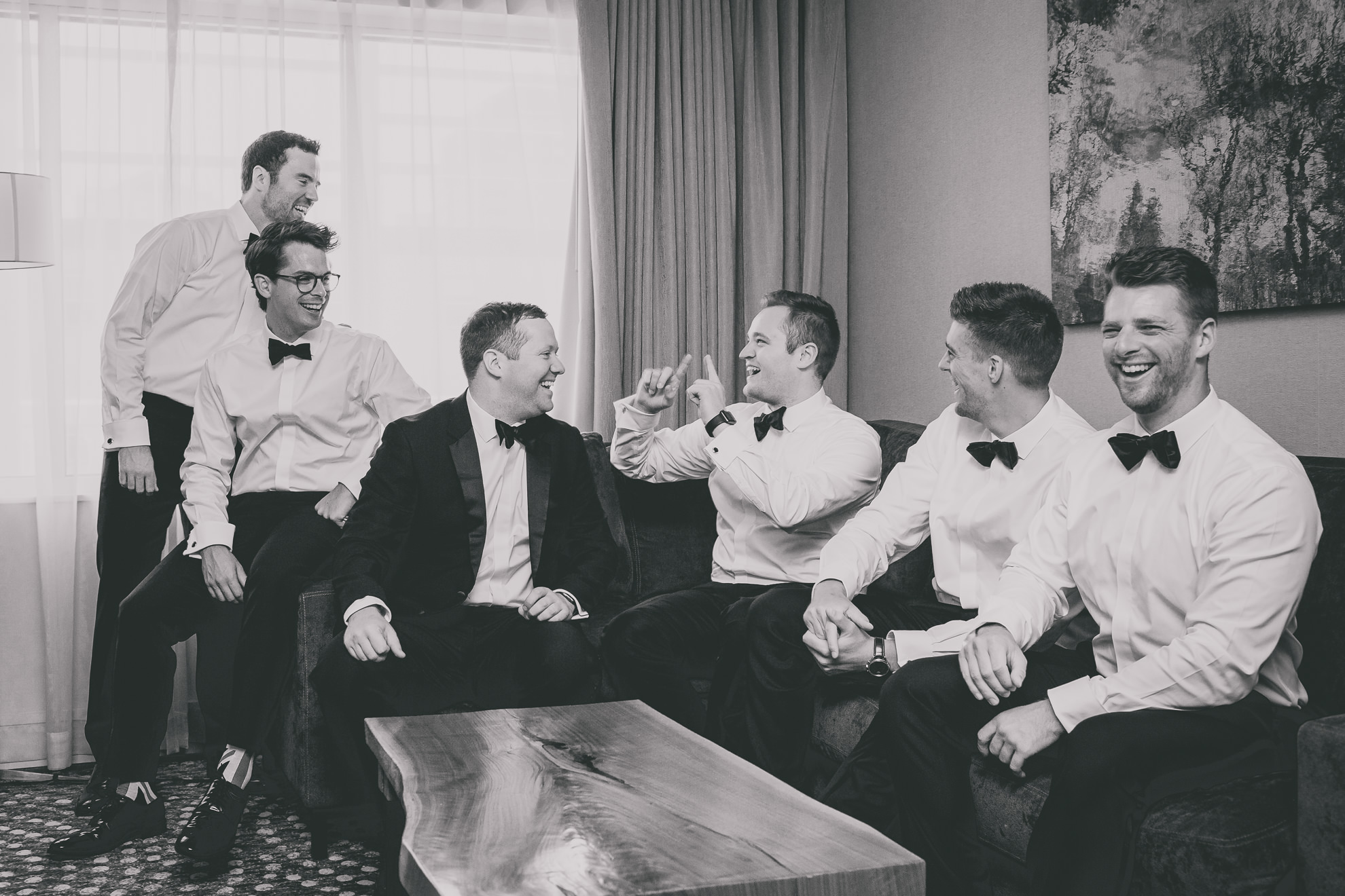 groomsman laugh and relax while getting ready for wedding ceremony at the Westin Hotel in Buffalo, NY