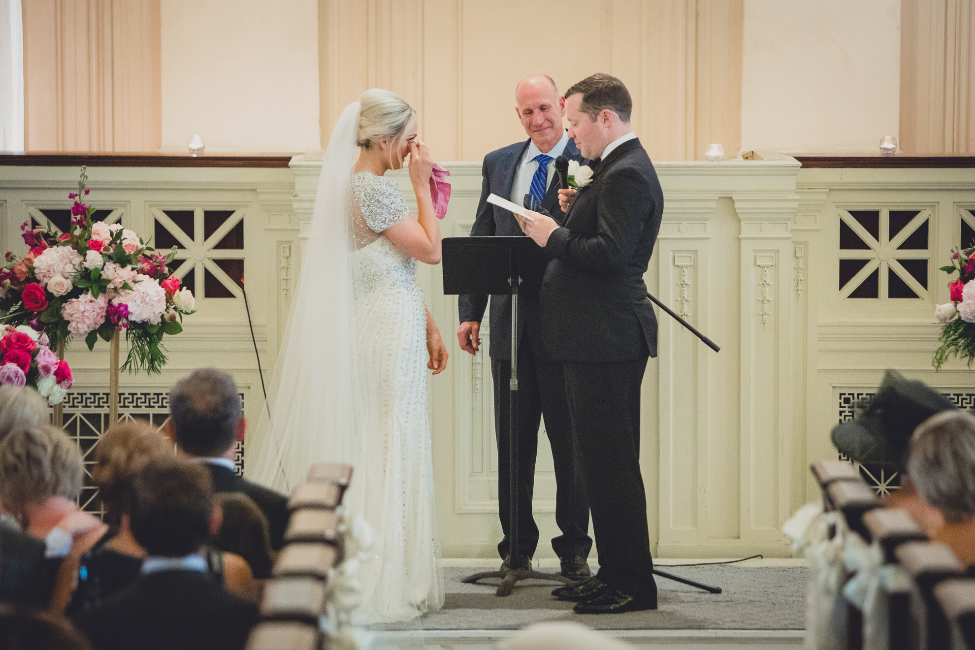 bride wipes tears during vows during wedding ceremony at Karpeles Manuscript Library in Buffalo, NY