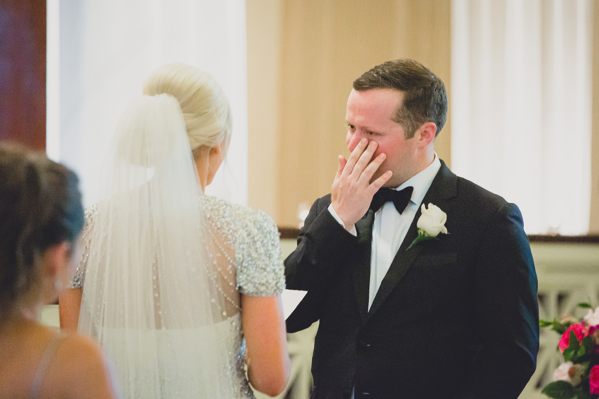 groom wipes tears during vows during wedding ceremony at Karpeles Manuscript Library in Buffalo, NY