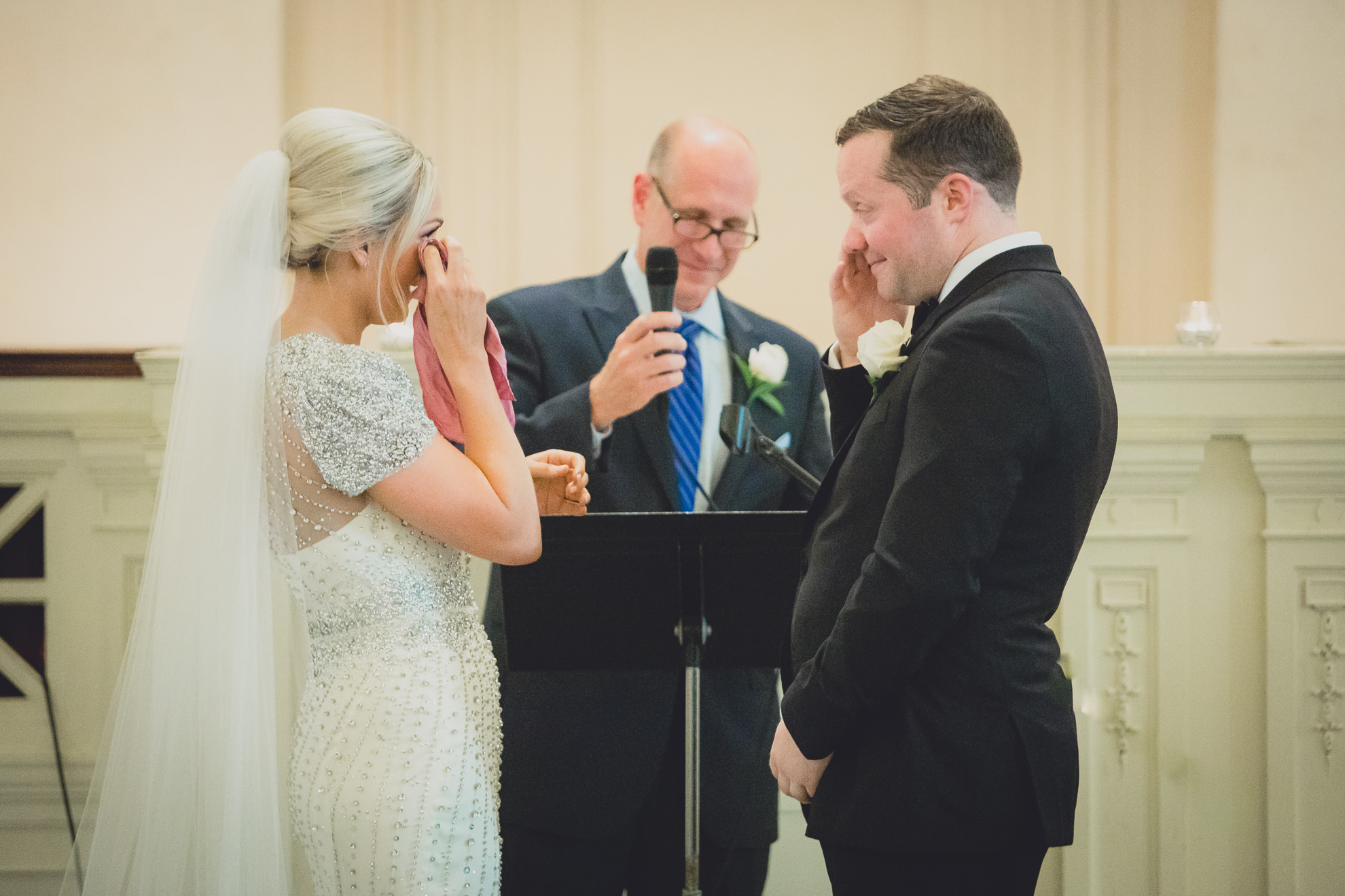 bride and groom wipe tears during wedding ceremony at Karpeles Manuscript Library in Buffalo, NY
