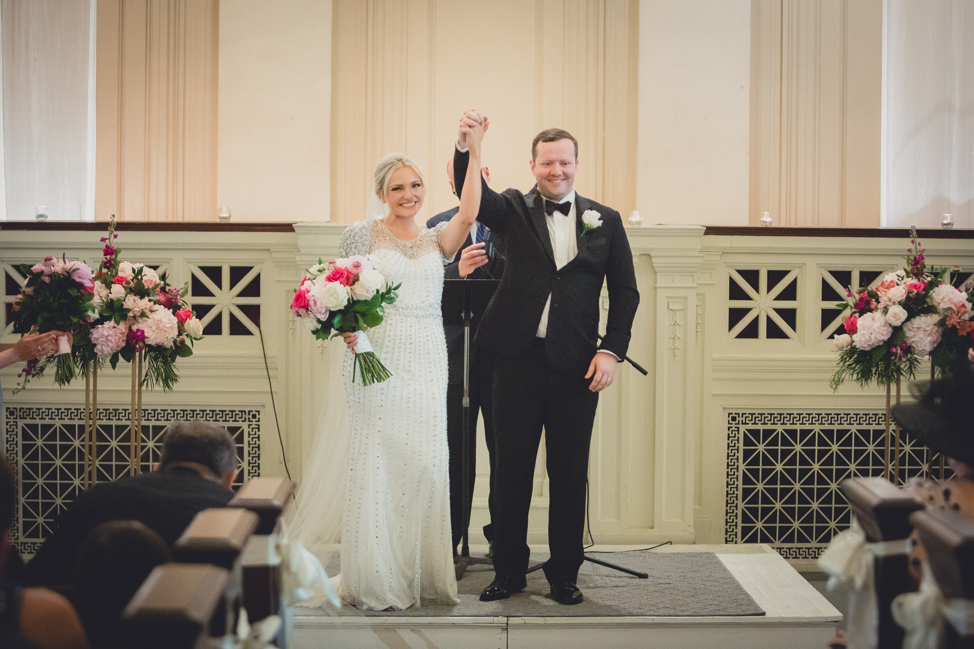 bride and groom raise arms in celebration after wedding ceremony at Karpeles Manuscript Library in Buffalo, NY