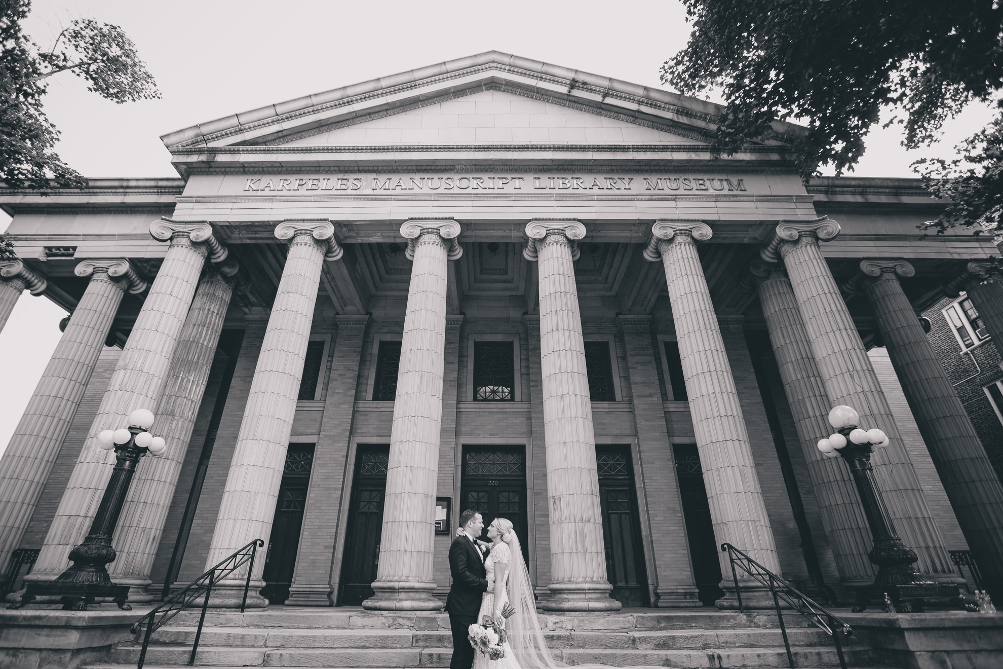 Bride and groom pose for wedding portrait on front steps of Karpeles Manuscript library in Buffalo, NY