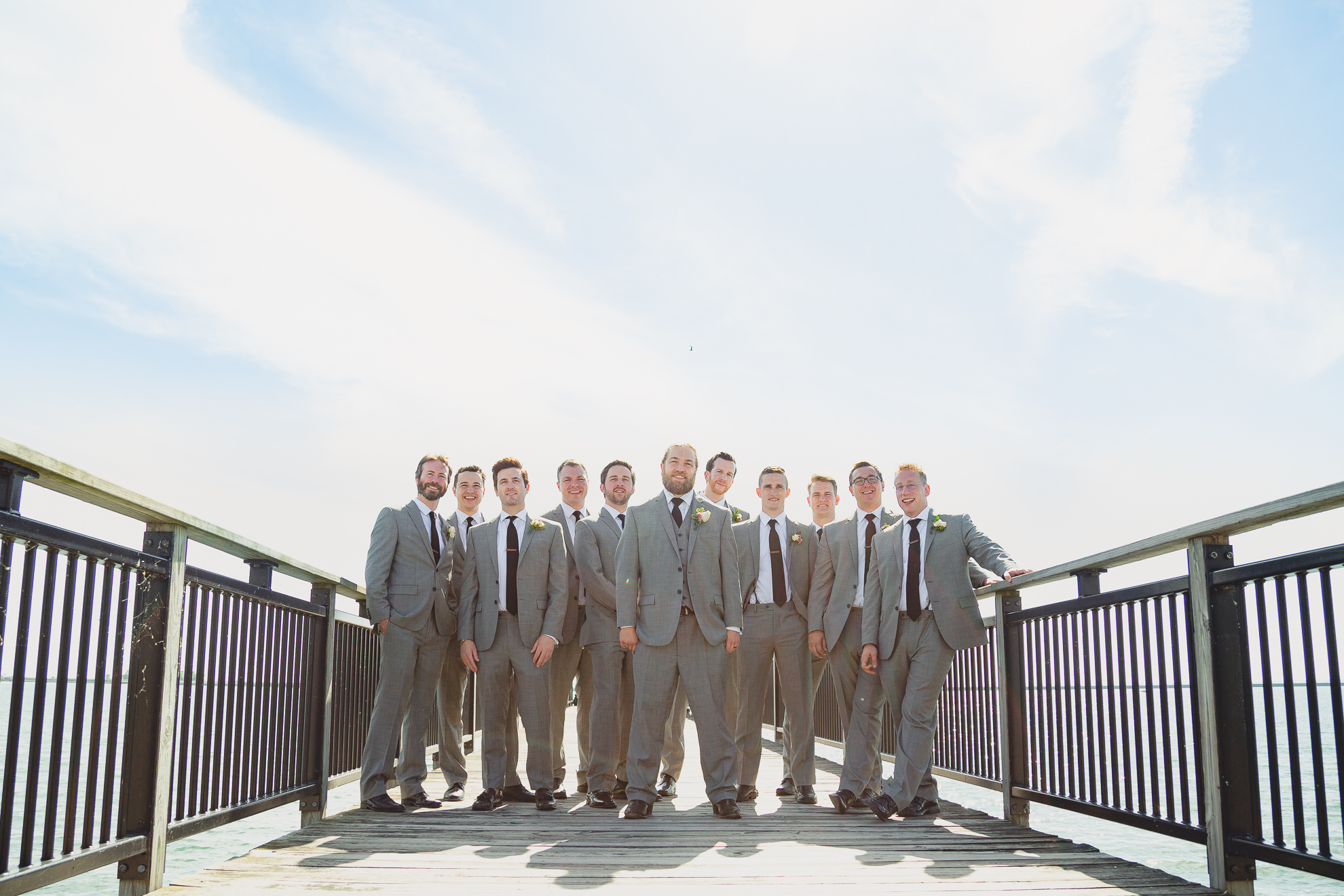 groom and groomsmen bride pose for photographer at wedding on pier at Gallagher Beach on Outer Harbor of Buffalo, NY