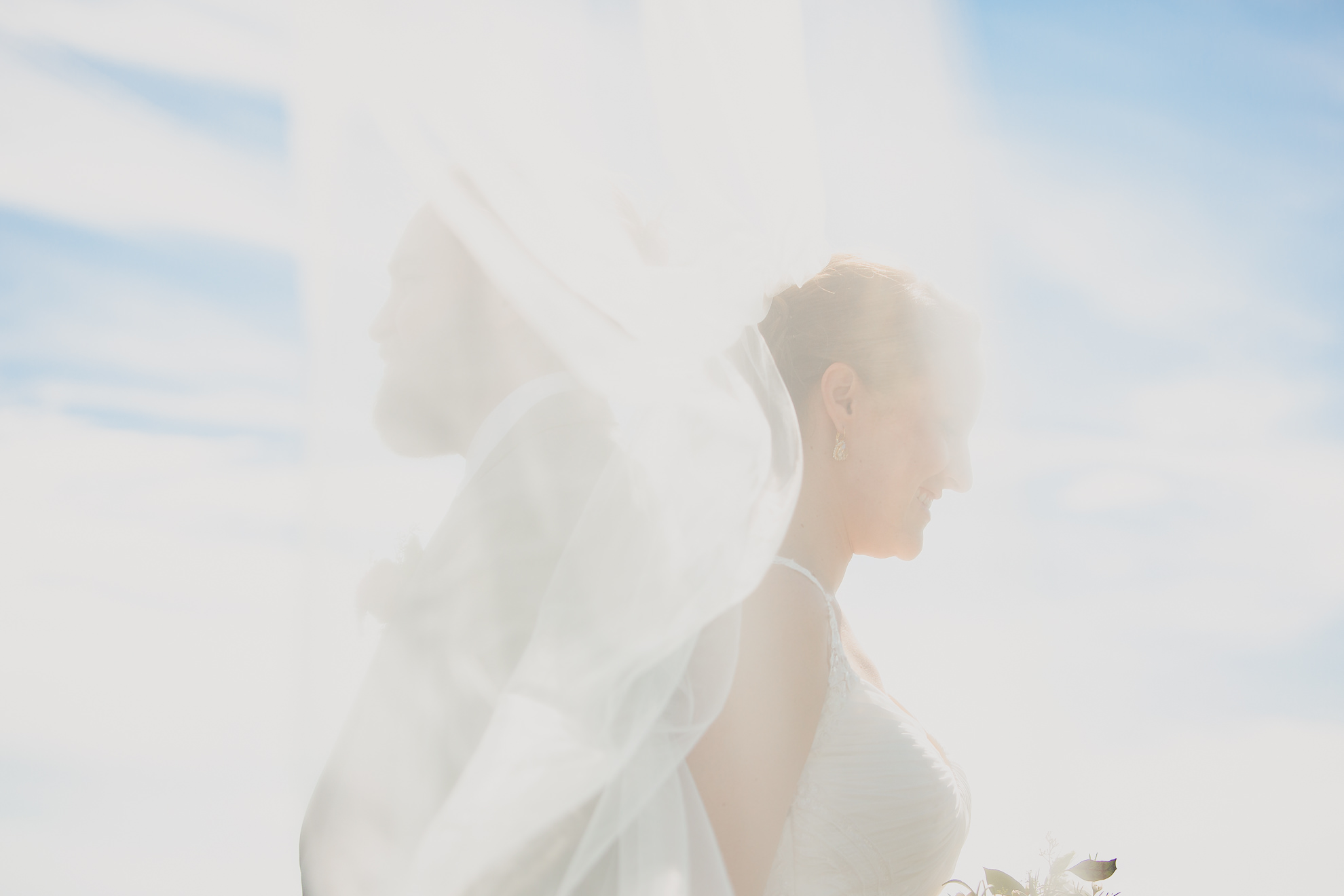 bride and groom pose for photographer at wedding on pier at Gallagher Beach on Outer Harbor of Buffalo, NY