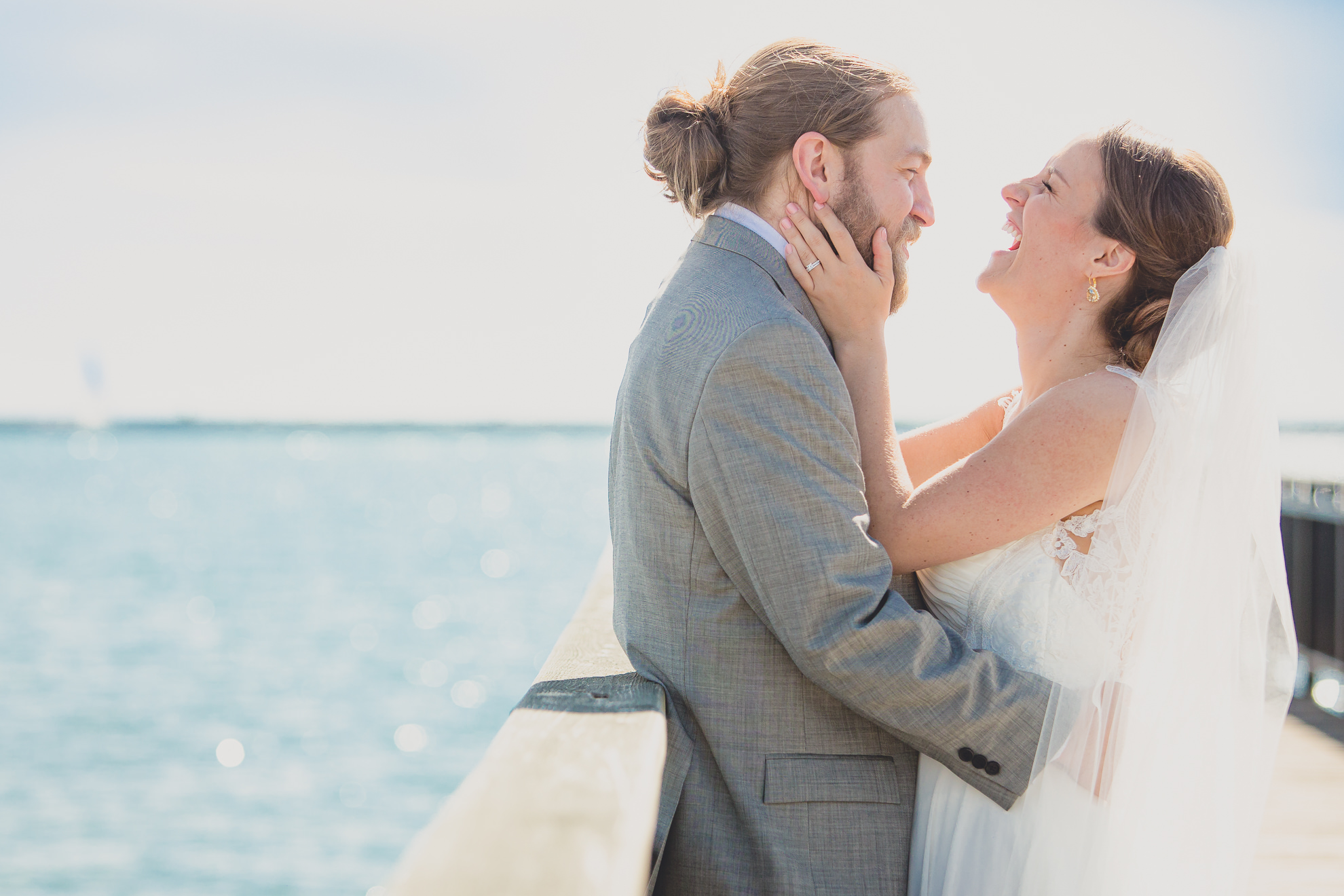 bride and groom pose for photographer at wedding on pier at Gallagher Beach on Outer Harbor of Buffalo, NY