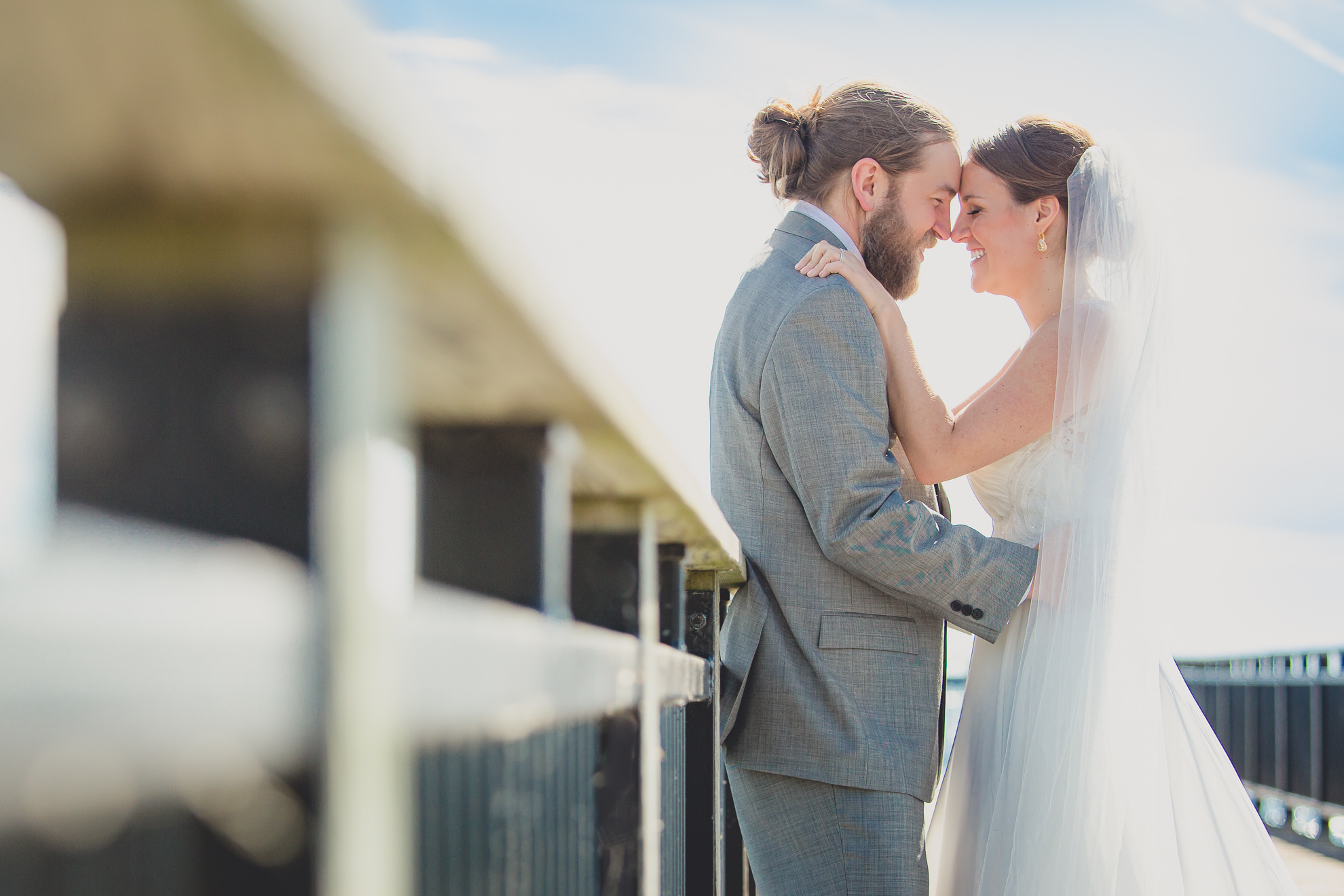 bride and groom pose for photographer at wedding on pier at Gallagher Beach on Outer Harbor of Buffalo, NY