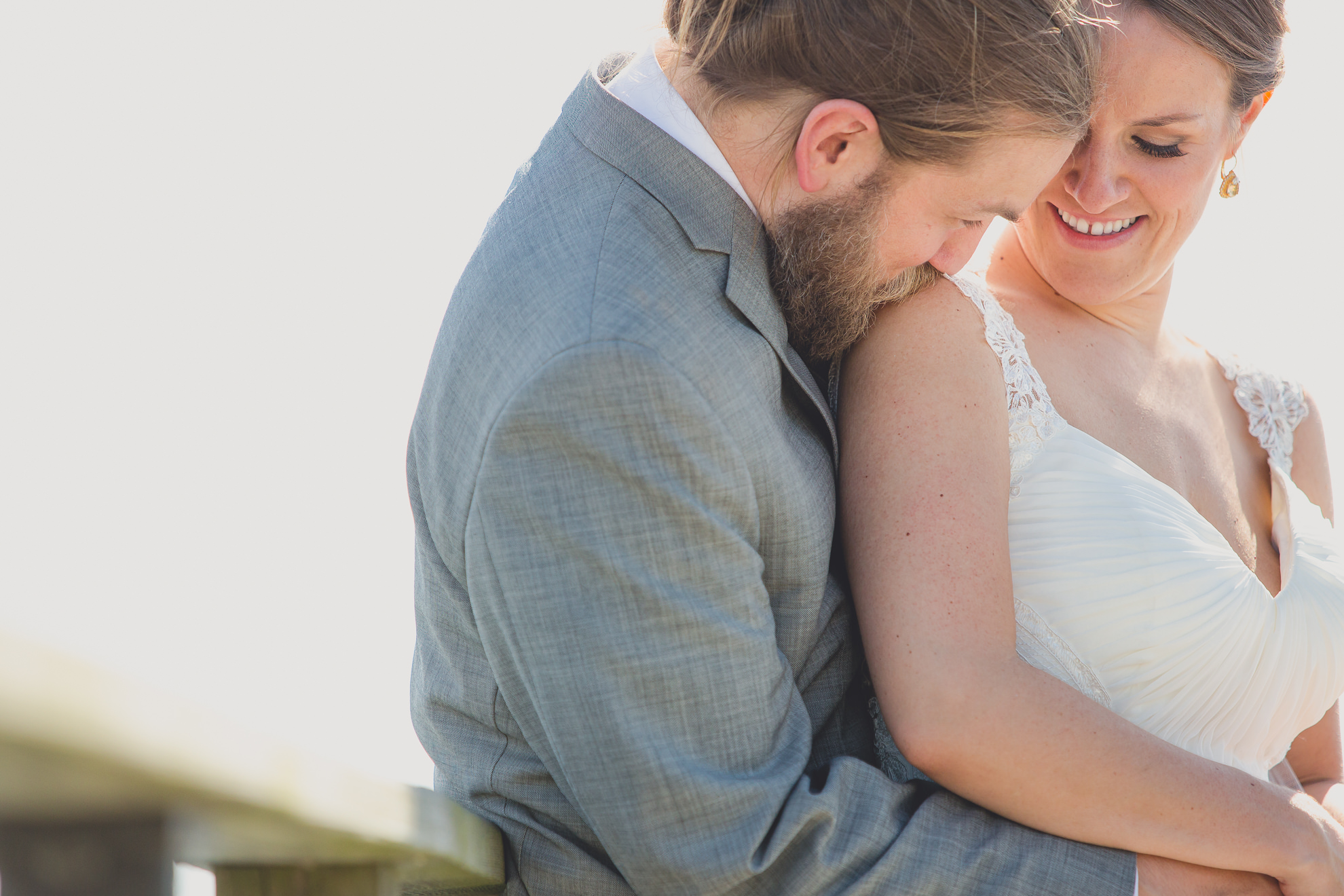bride and groom pose for photographer at wedding on pier at Gallagher Beach on Outer Harbor of Buffalo, NY