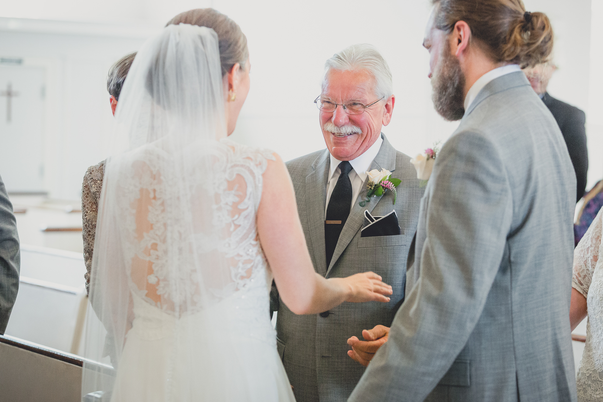 father of groom smiles at bride during wedding ceremony at St. John the Baptist church in Kenmore, NY