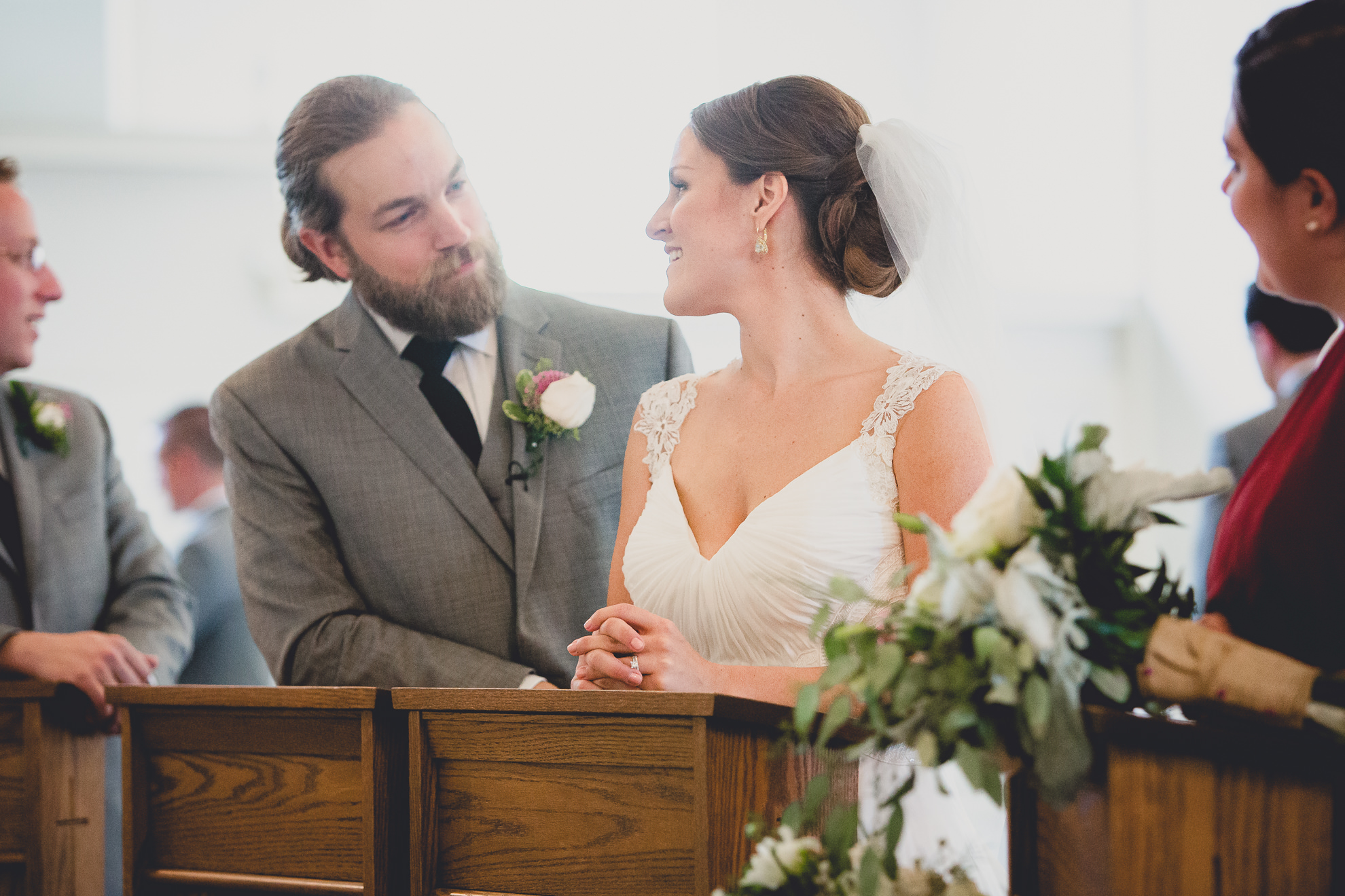 bride and groom smile at each other during wedding ceremony at St. John the Baptist church in Kenmore, NY