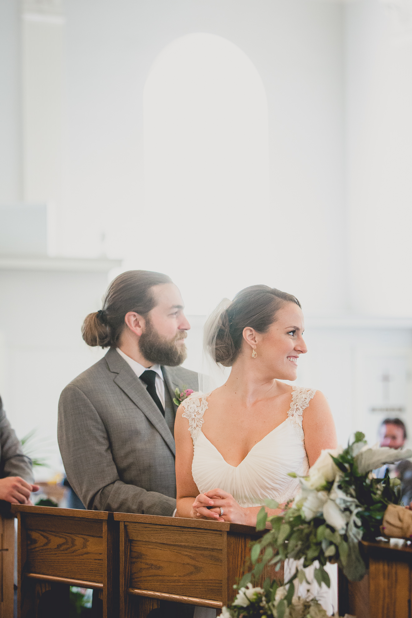 bride and groom smiles at guests during wedding ceremony at St. John the Baptist church in Kenmore, NY