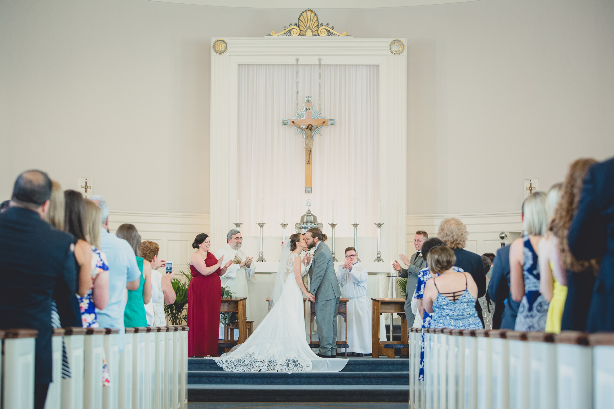 bride and groom kiss during wedding ceremony at St. John the Baptist church in Kenmore, NY