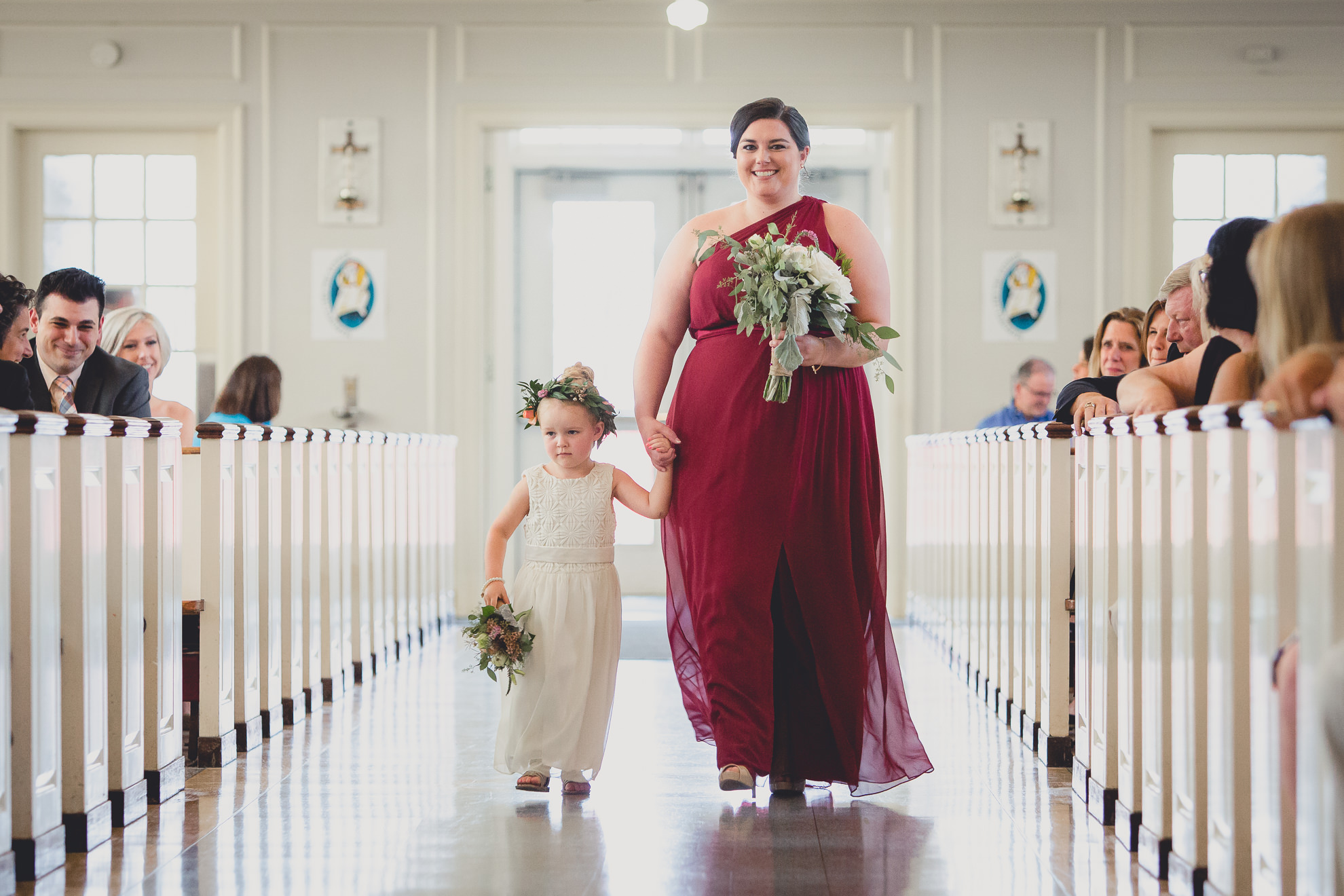 maid of honor and flower girl walk down aisle during wedding ceremony at St. John the Baptist church in Kenmore, NY