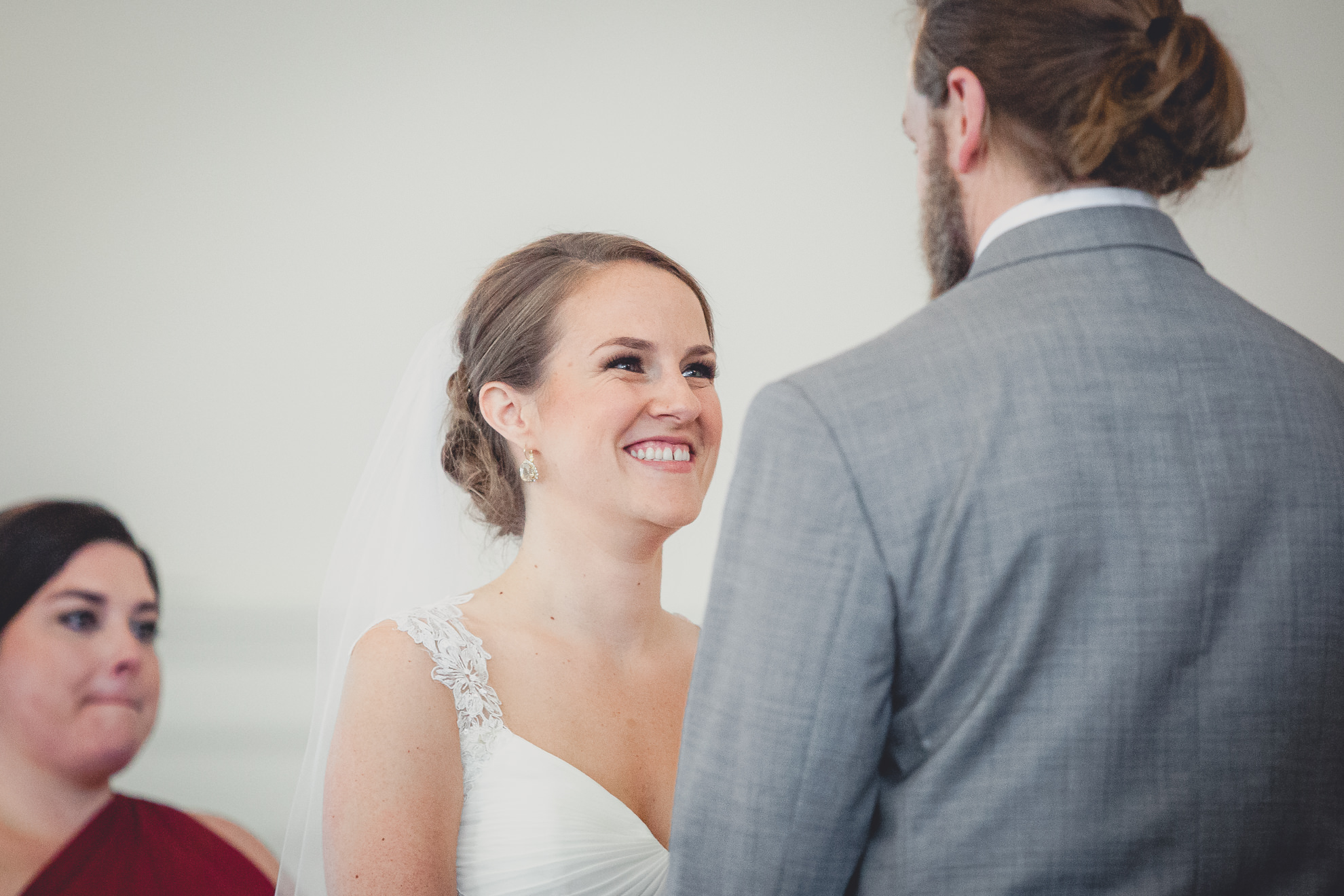 bride smiles at groom during wedding ceremony at St. John the Baptist church in Kenmore, NY