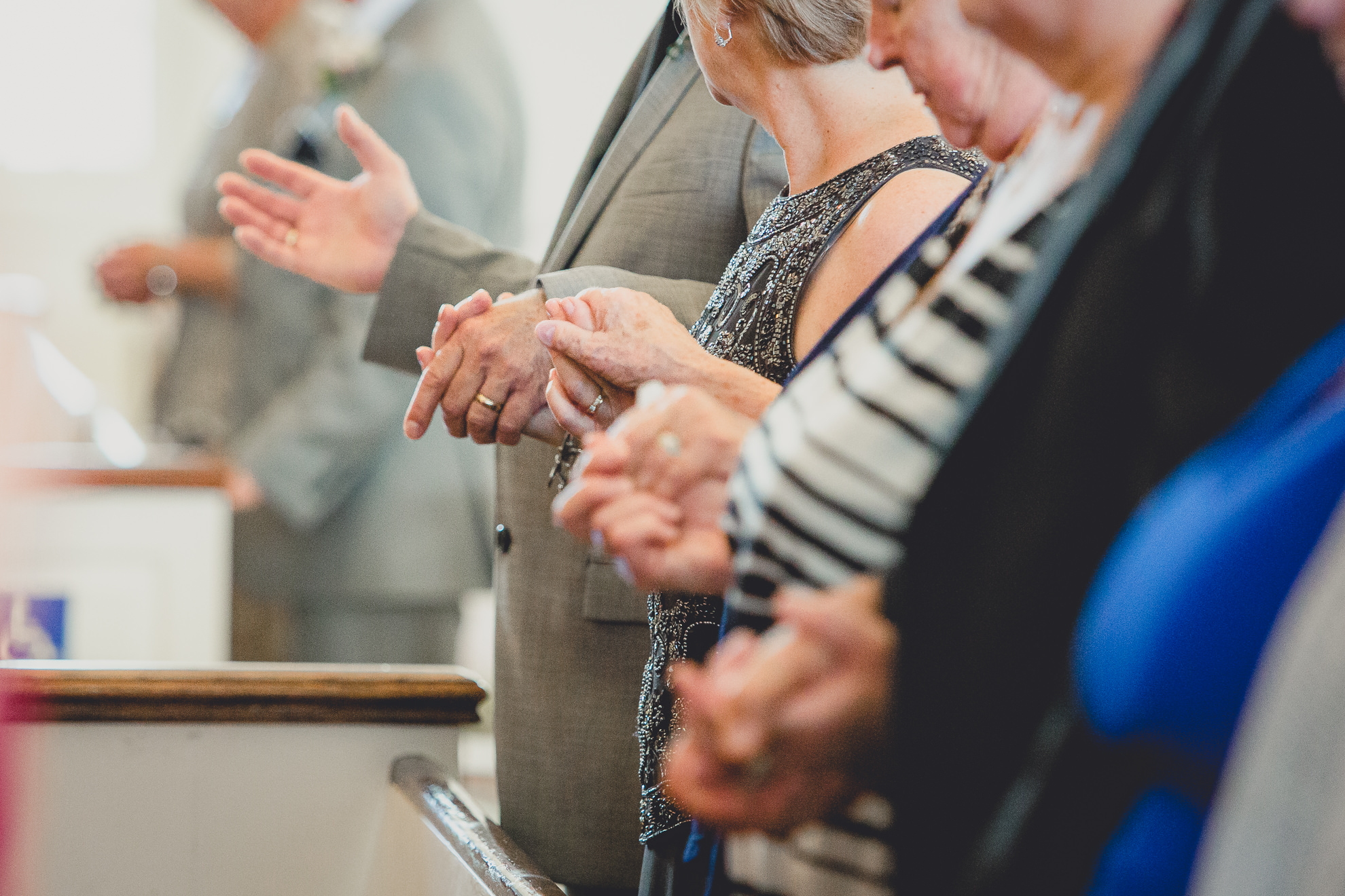 guests hold hands and pray during wedding ceremony at St. John the Baptist church in Kenmore, NY