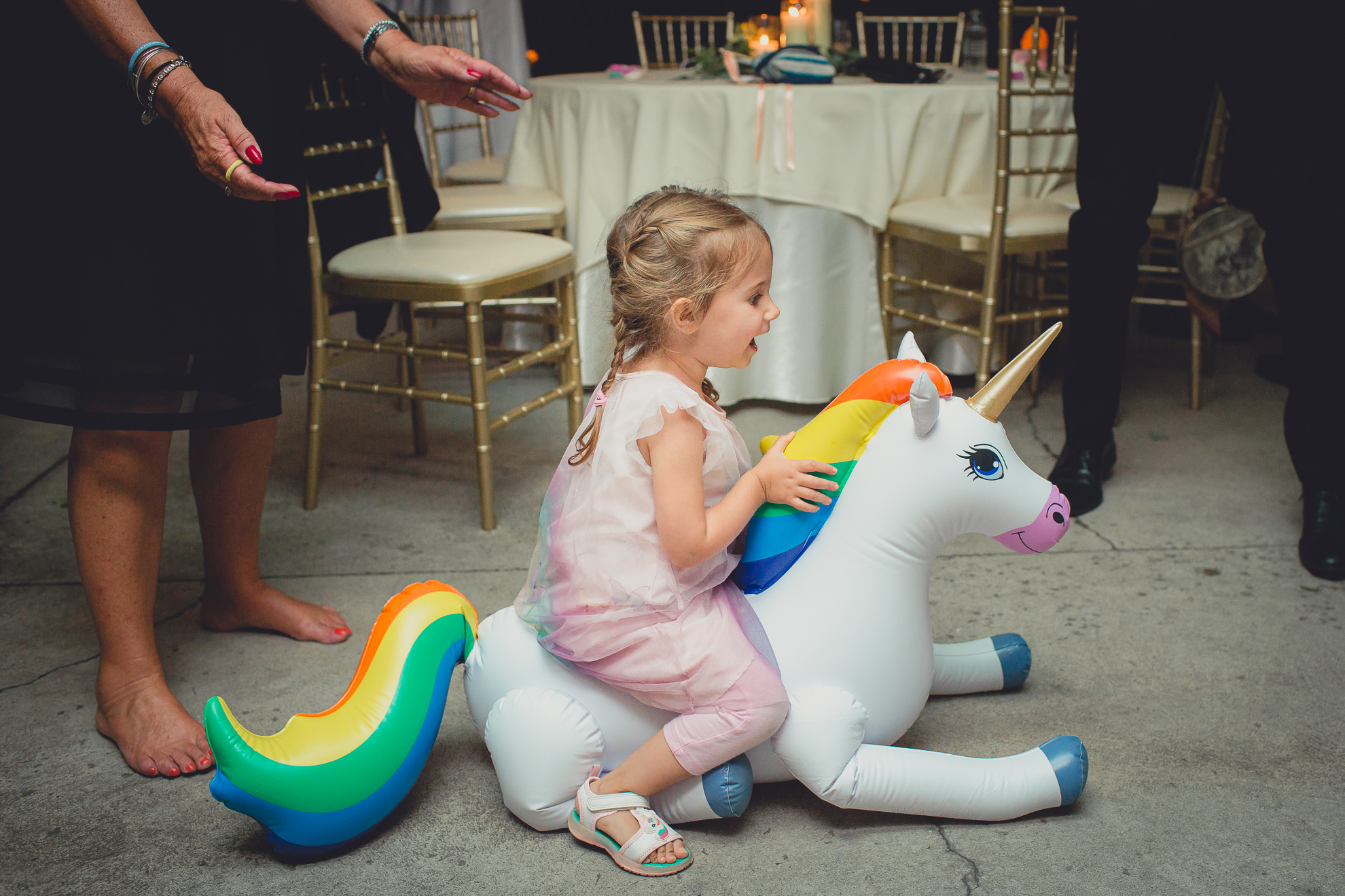 little girl sits on rainbow unicorn during wedding at Marcy Casino in Delaware Park in Buffalo, NY
