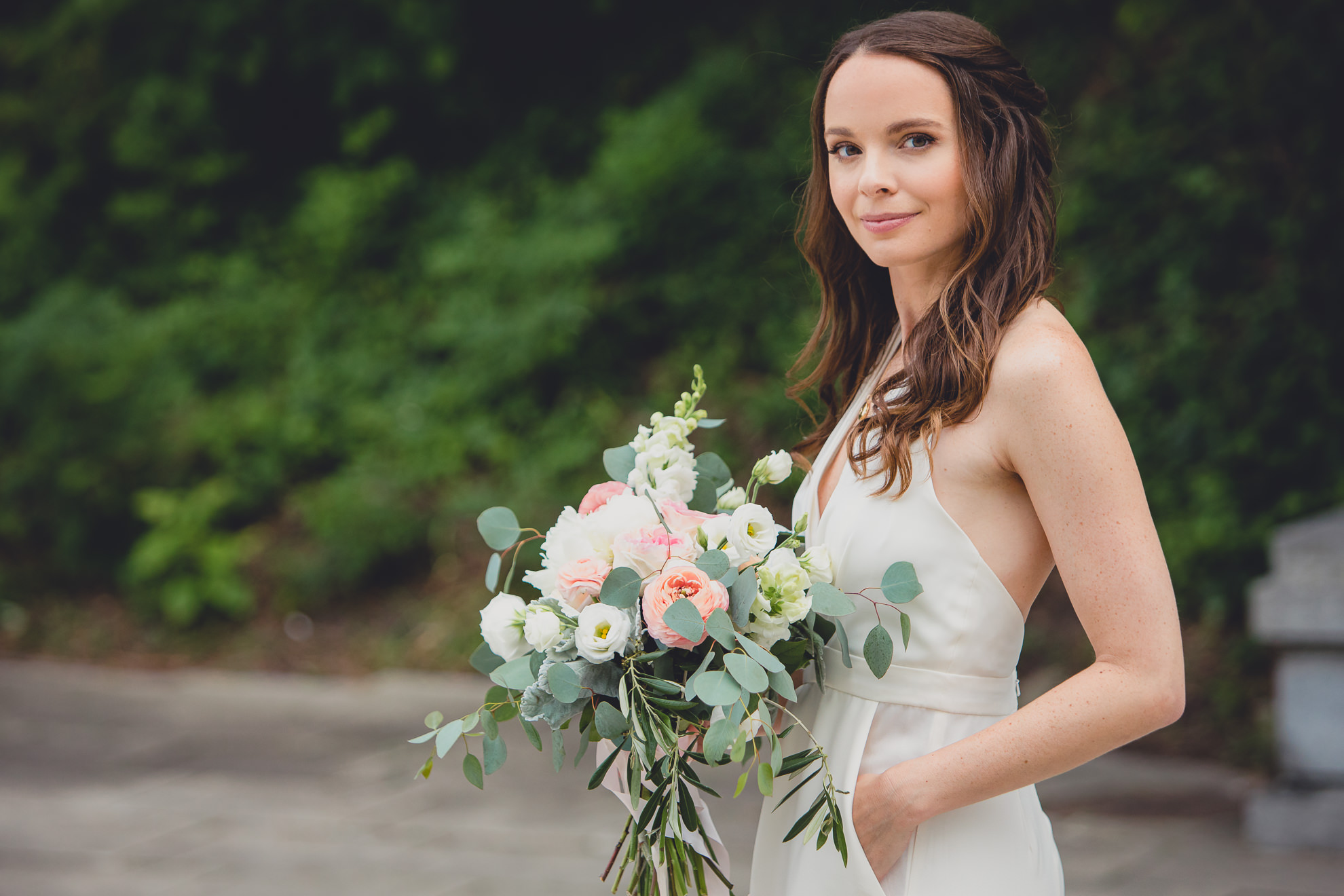 bride smiles for photographer on wedding day ceremony in front of Albright Knox in Delaware Park in Buffalo, NY