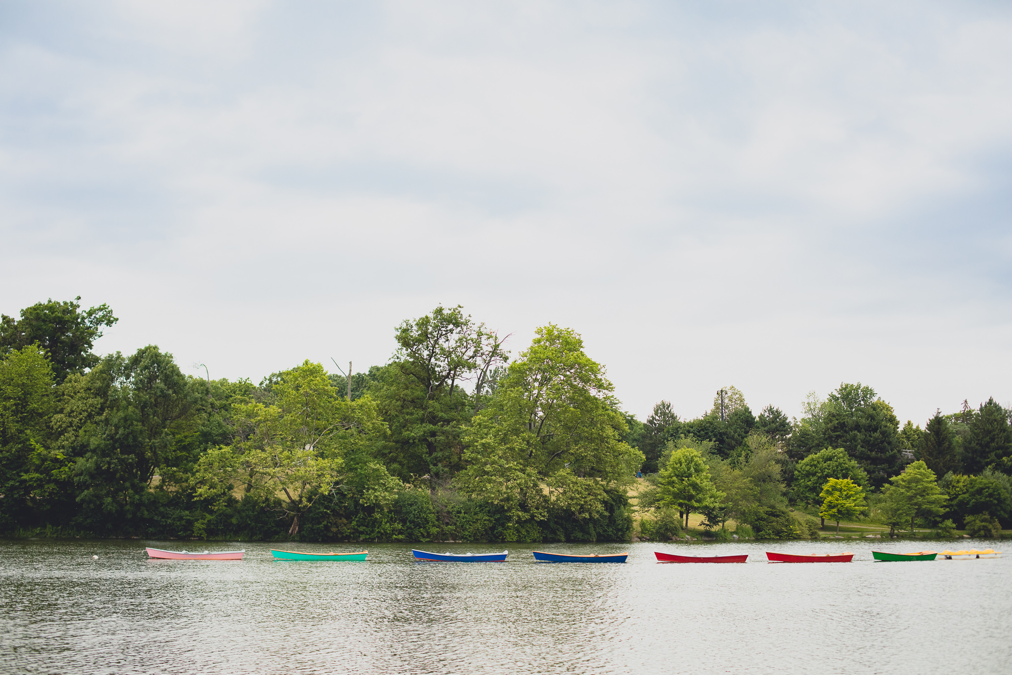 rainbow row boats float in water during wedding ceremony in front of Hoyt Lake at Marcy Casino in Delaware Park in Buffalo, NY