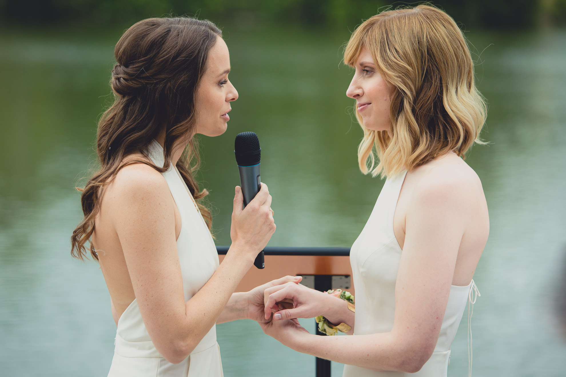 brides say vows during wedding ceremony in front of Hoyt Lake at Marcy Casino in Delaware Park in Buffalo, NY