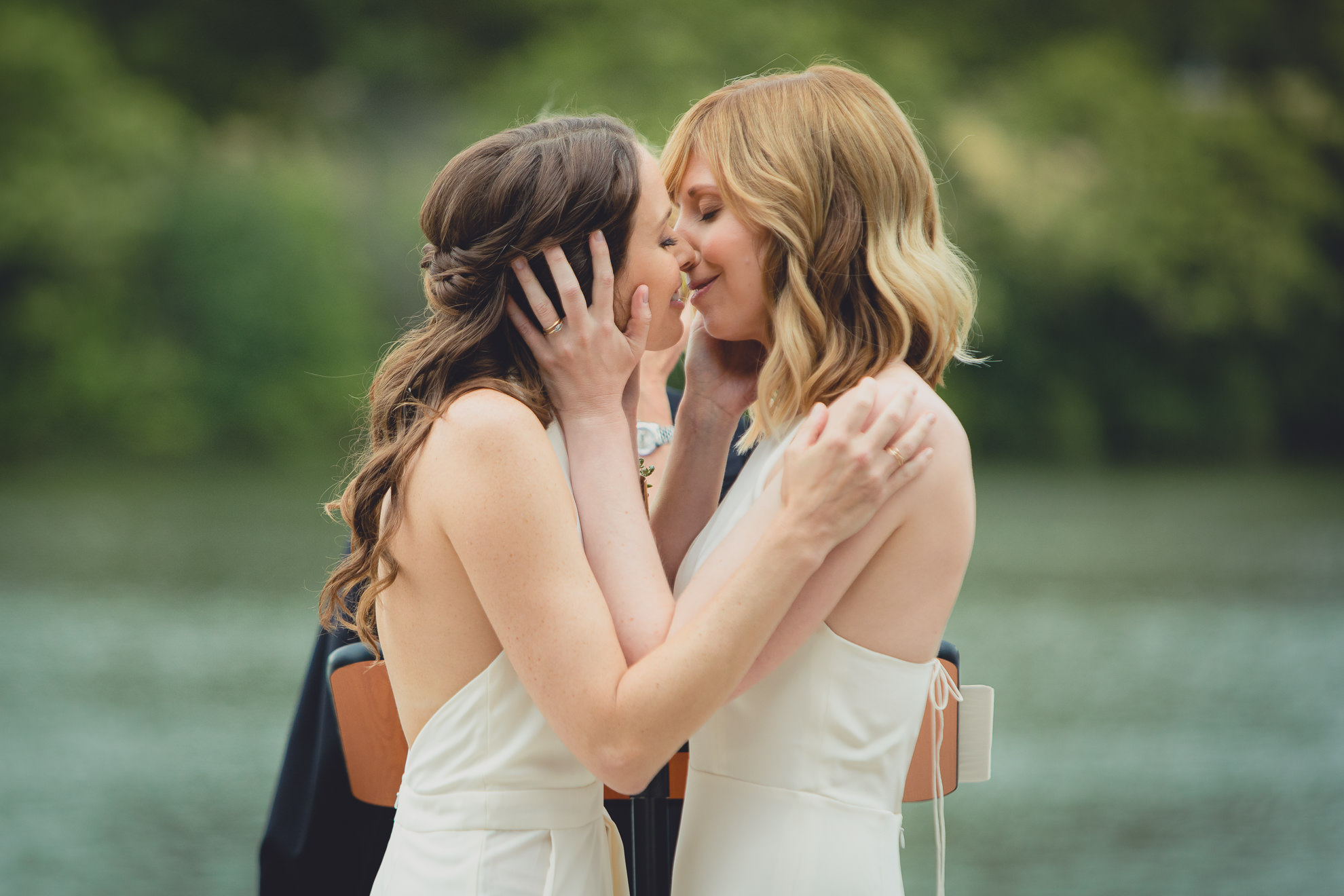 brides kiss during wedding ceremony in front of Hoyt Lake at Marcy Casino in Delaware Park in Buffalo, NY