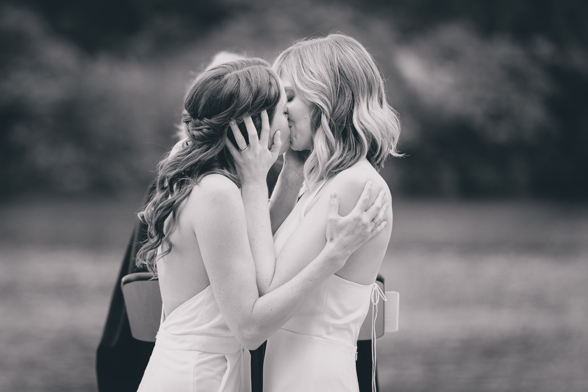brides kiss during wedding ceremony in front of Hoyt Lake at Marcy Casino in Delaware Park in Buffalo, NY