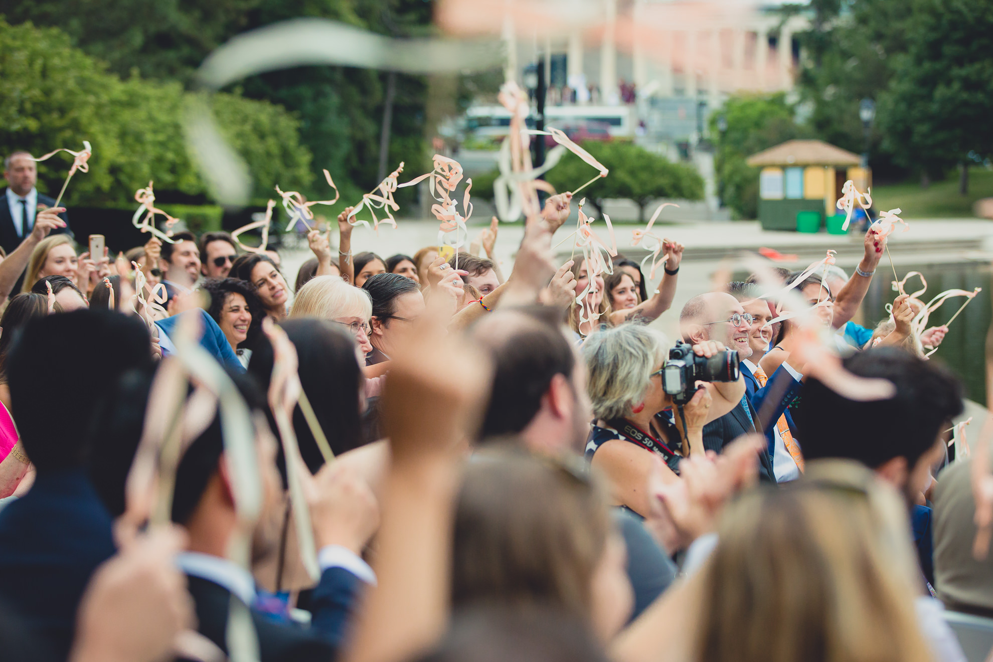 guests celebrate by waving streamers during wedding ceremony in front of Hoyt Lake at Marcy Casino in Delaware Park in Buffalo, NY