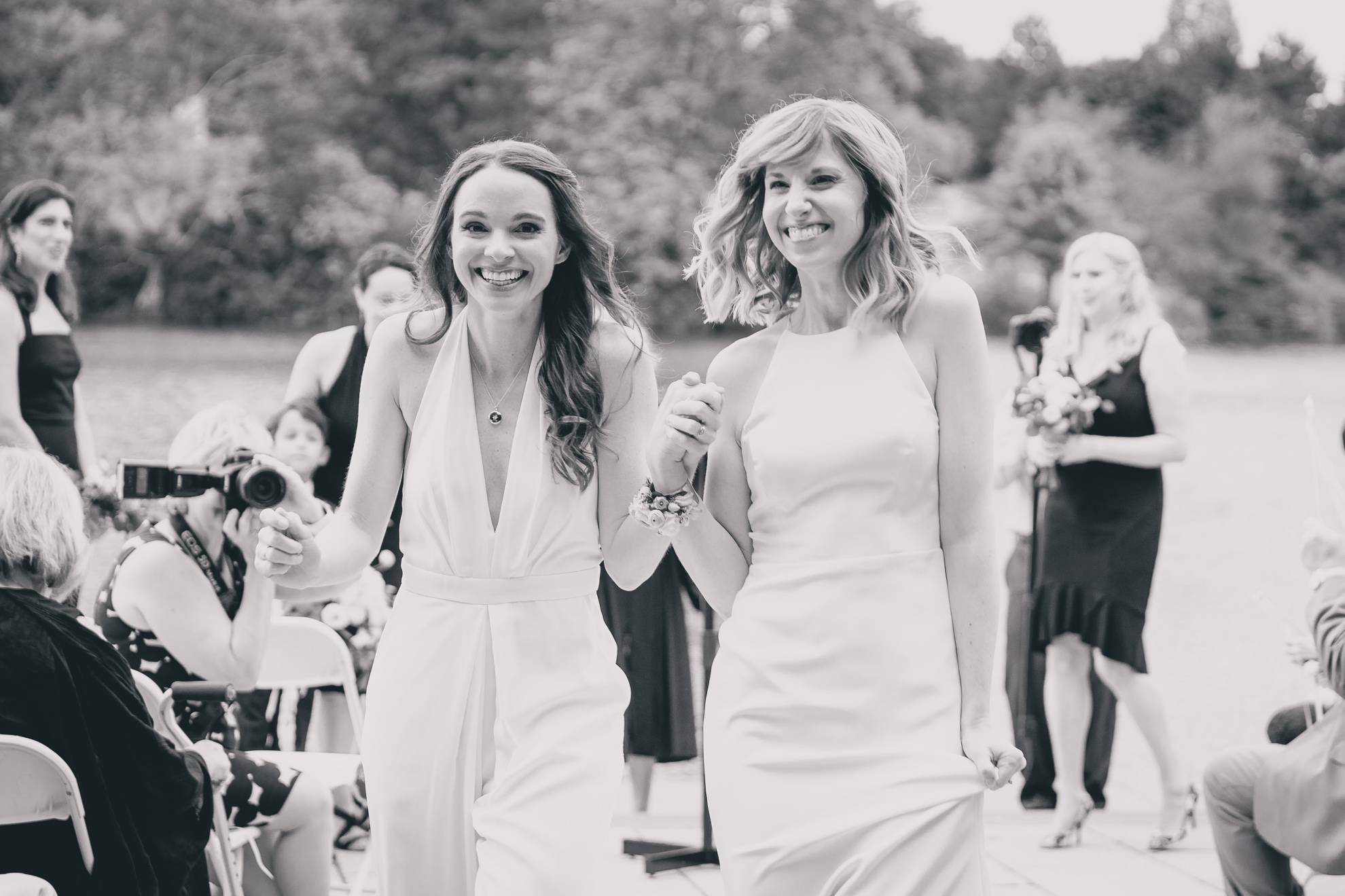 brides celebrate during wedding ceremony in front of Hoyt Lake at Marcy Casino in Delaware Park in Buffalo, NY