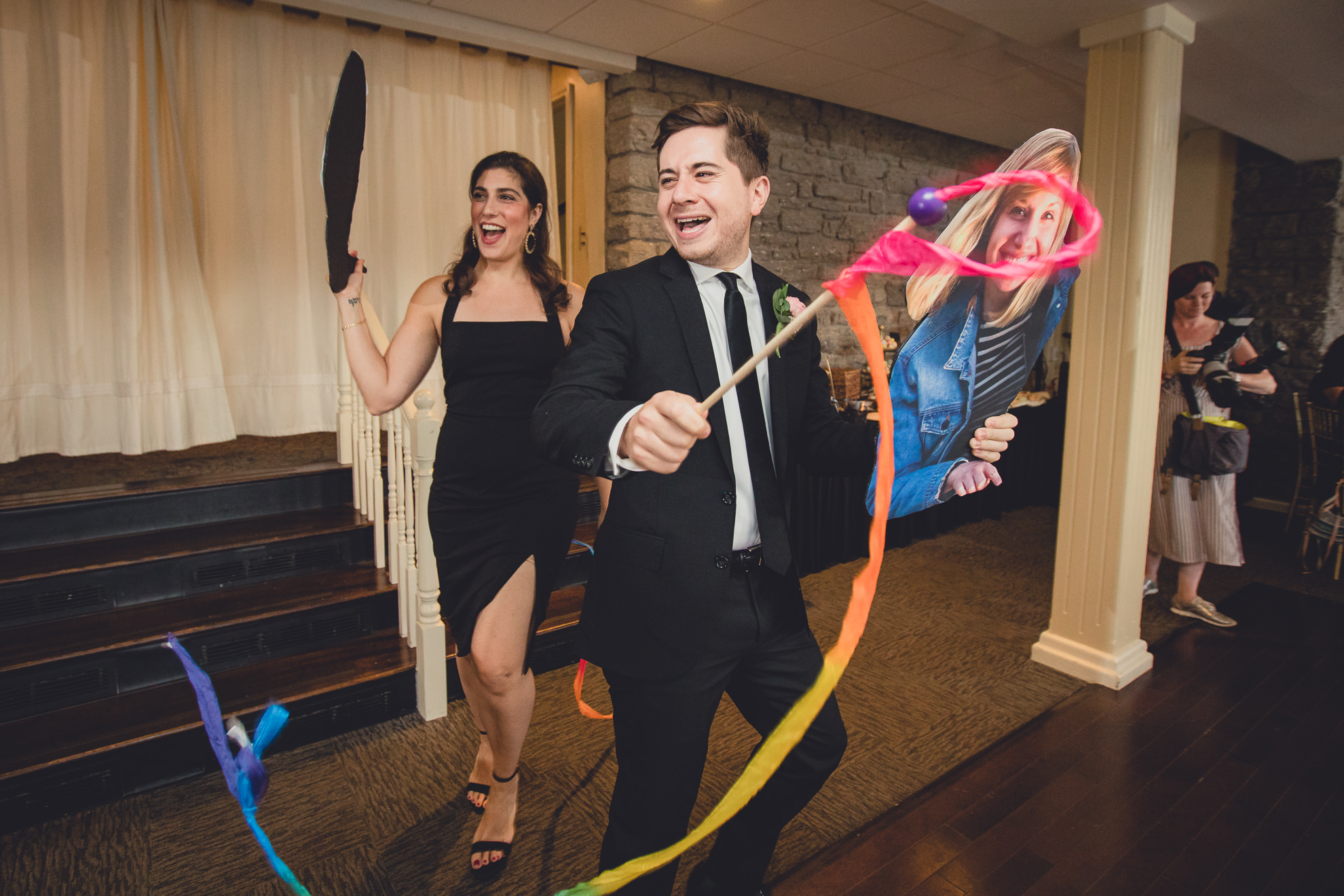 wedding party enters reception with rainbow streamers during wedding at Marcy Casino in Delaware Park in Buffalo, NY