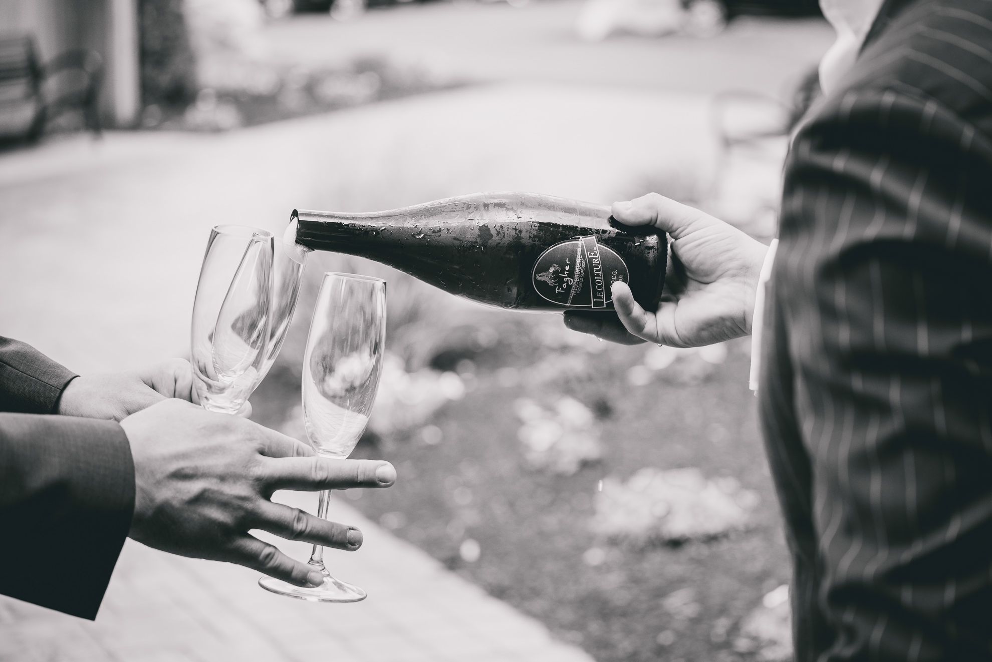 grooman pours champagne at Strathallan Hotel in Rochester, NY before wedding